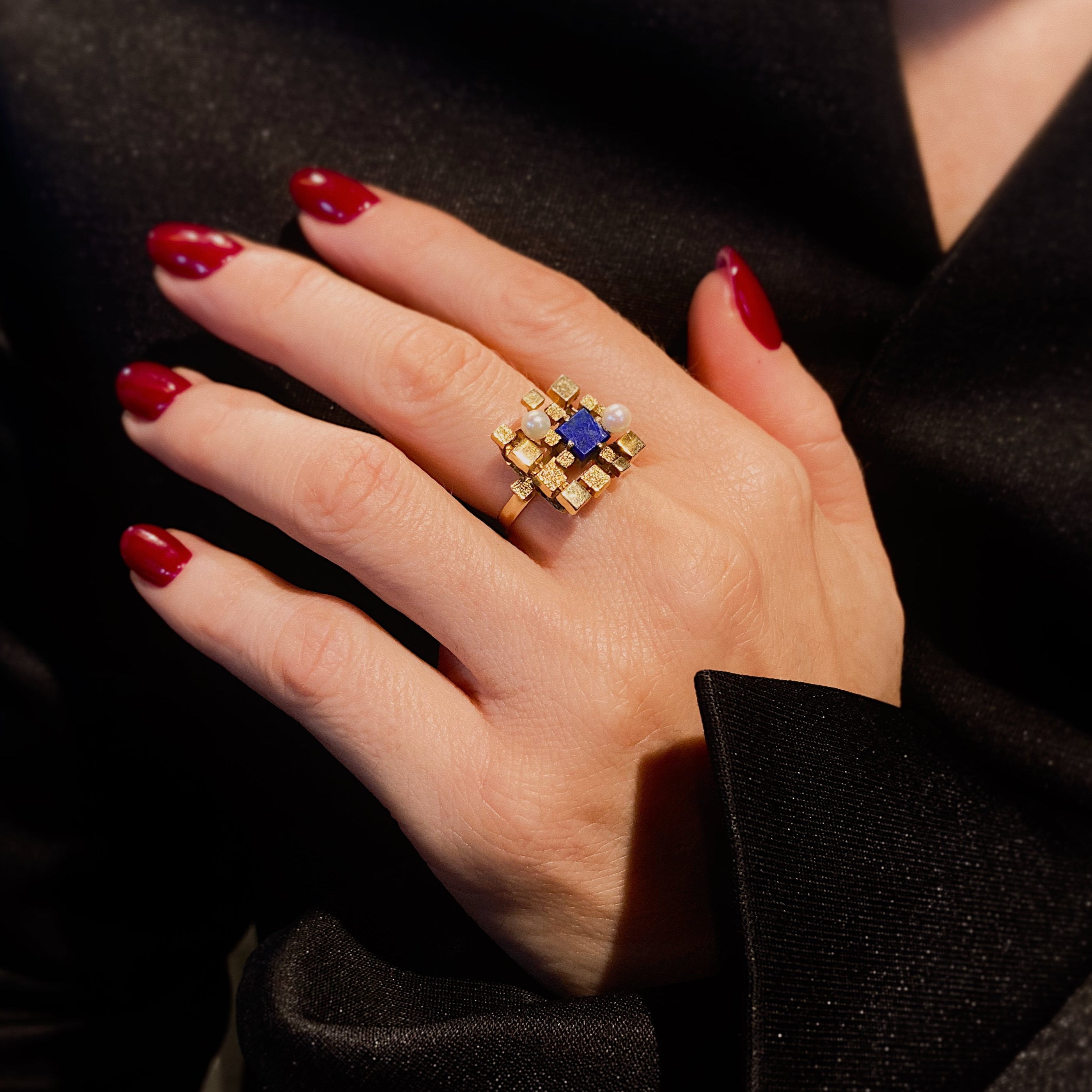 Woman model's hand wearing the modernist vintage gold cocktail ring with lapis lazuli and pearls.