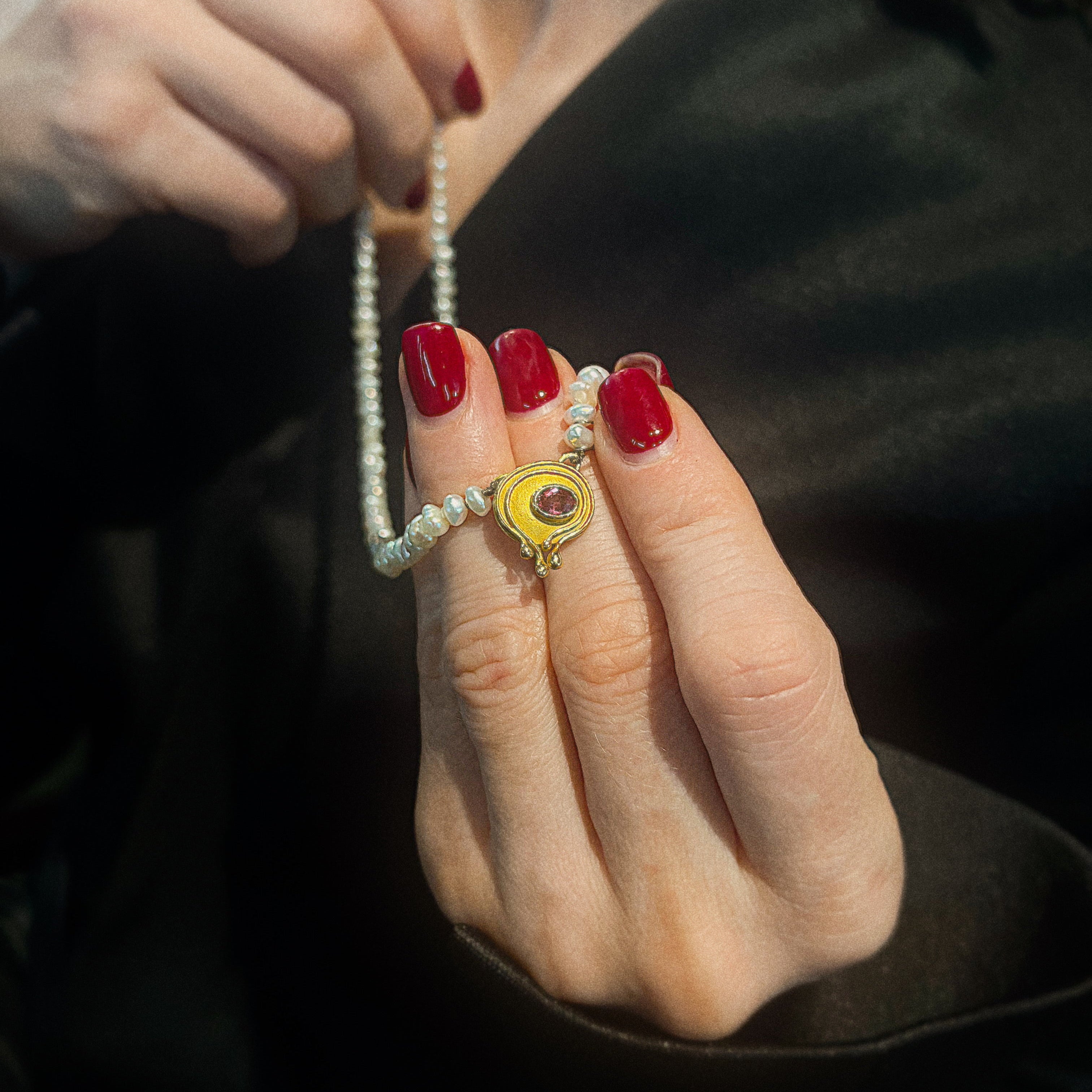 Model holding the vintage 1970s gold pearl necklace with tourmaline.