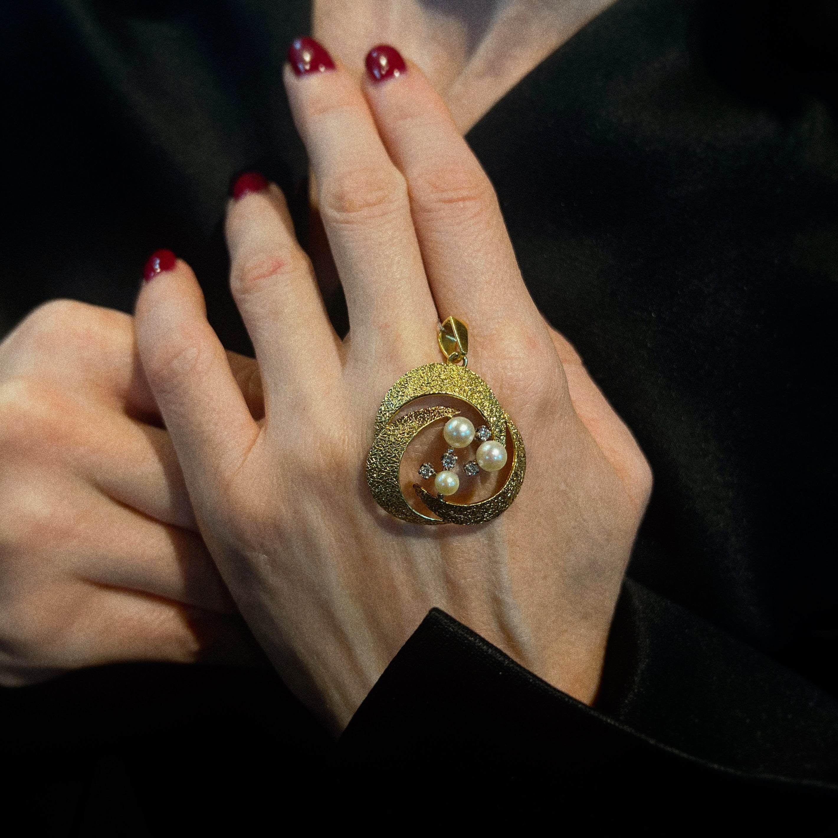 Model holding the vintage gold pendant with pearls and diamonds.