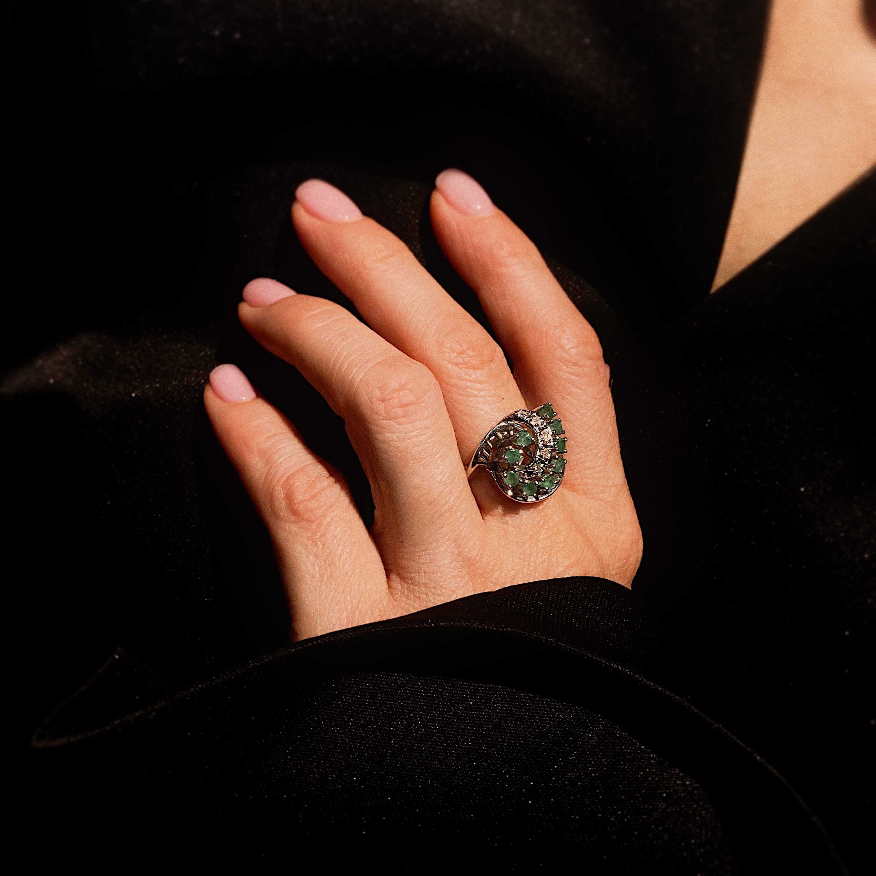 Model hand wearing the mid-century white gold cocktail ring with emeralds and diamonds.