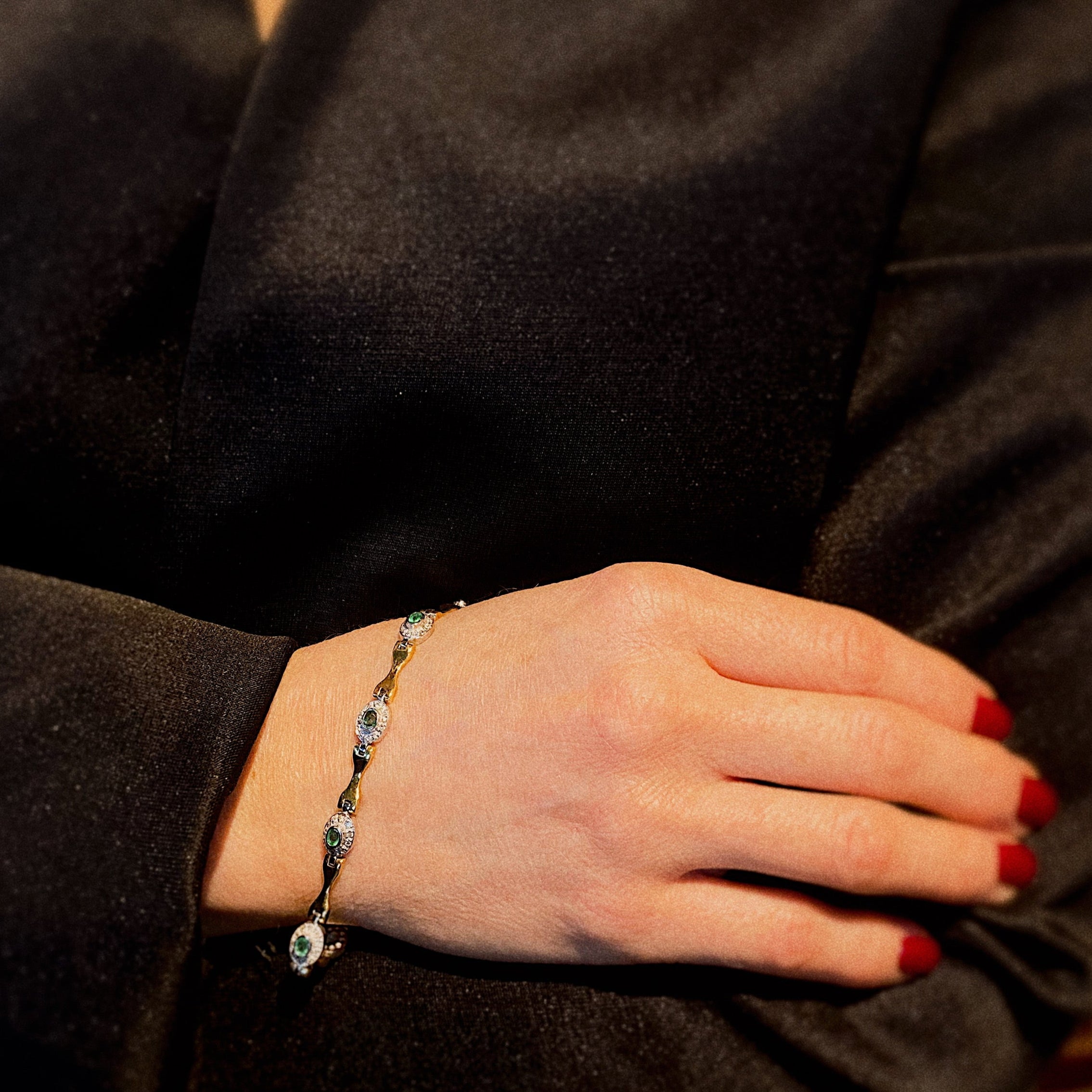 Model wearing the wo-tone gold vintage bracelet with emeralds and diamonds.