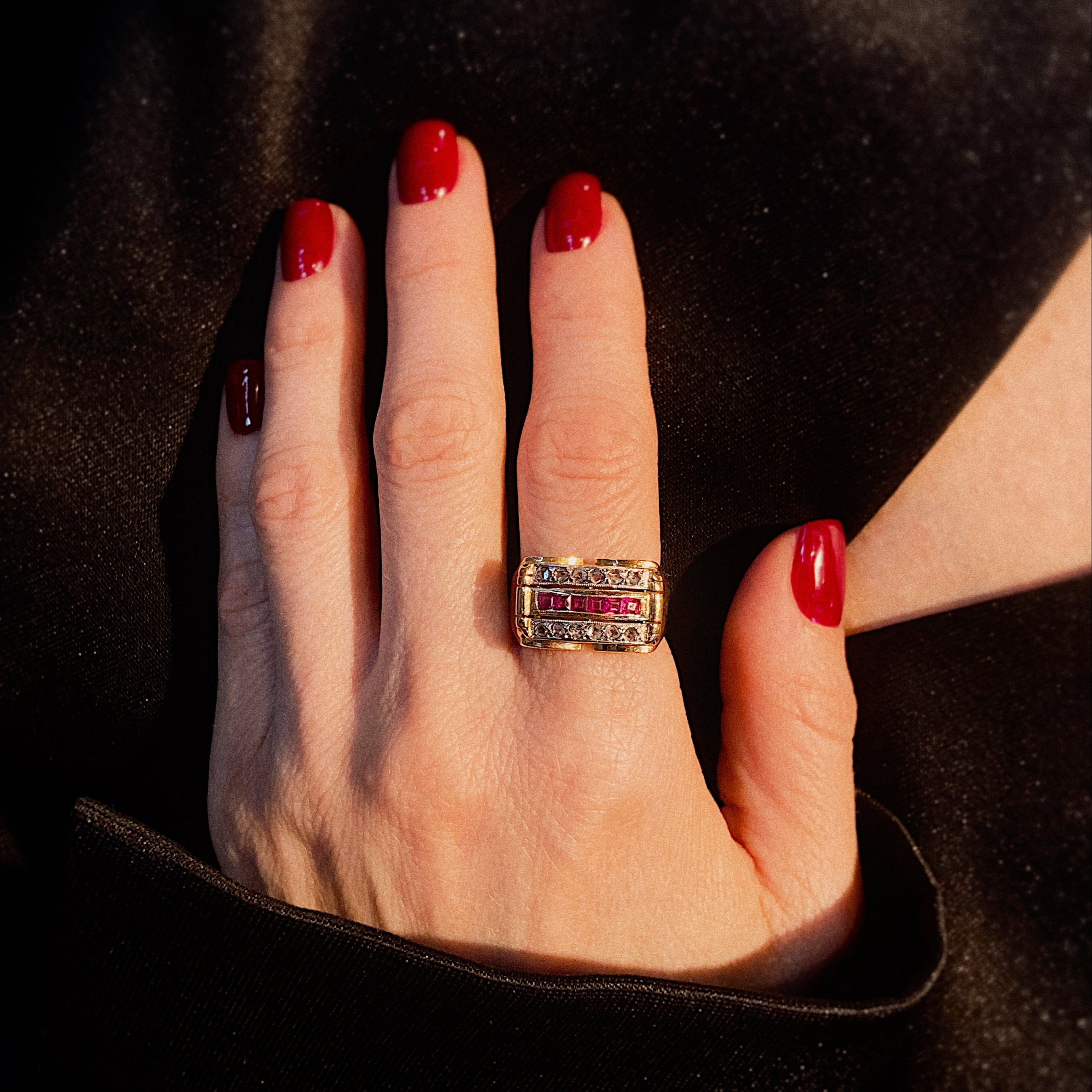 Model wearing contemporary art deco revival gold cocktail ring with rubies and diamonds.