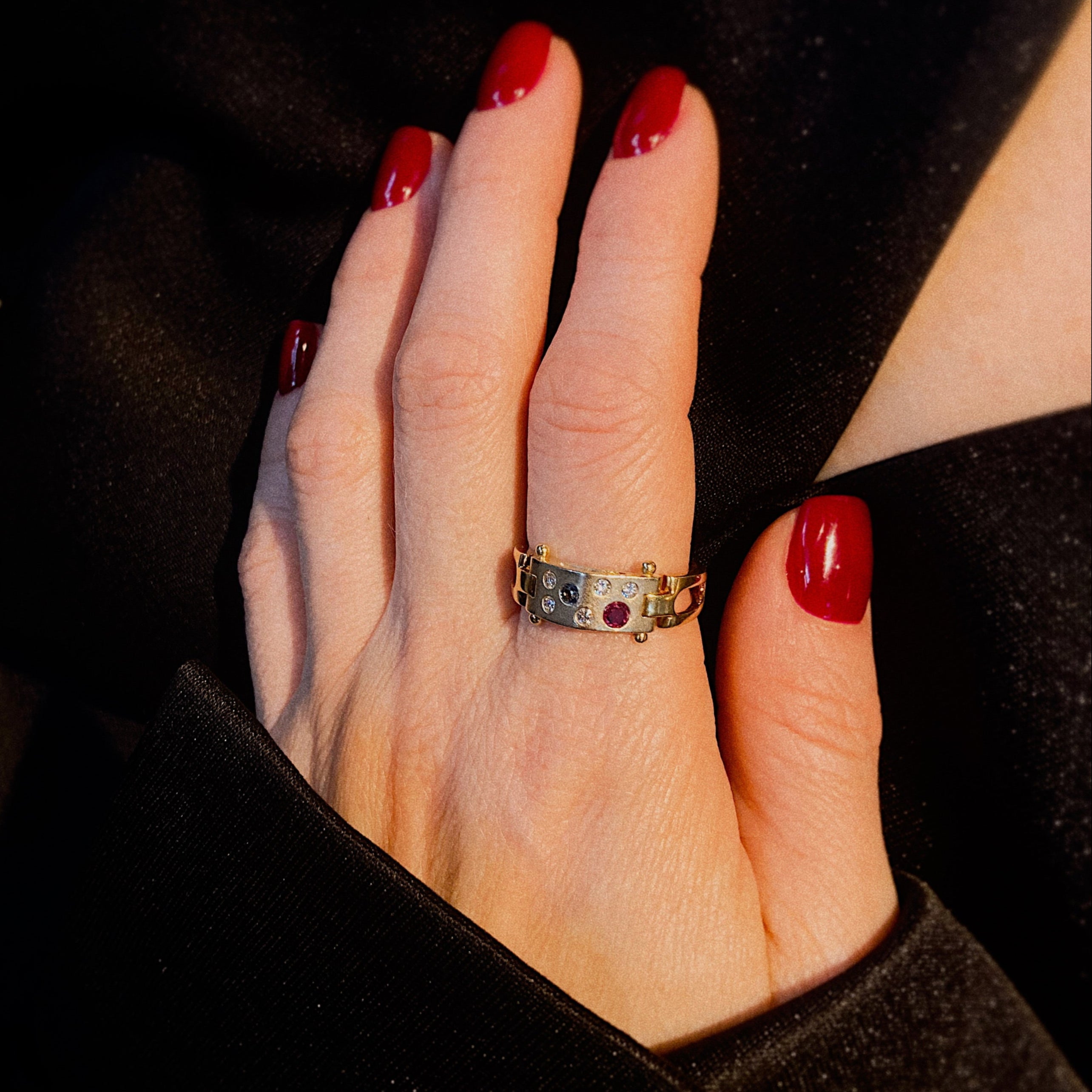 Model wearing the avant-garde two-tone gold ring with colored gemstones.