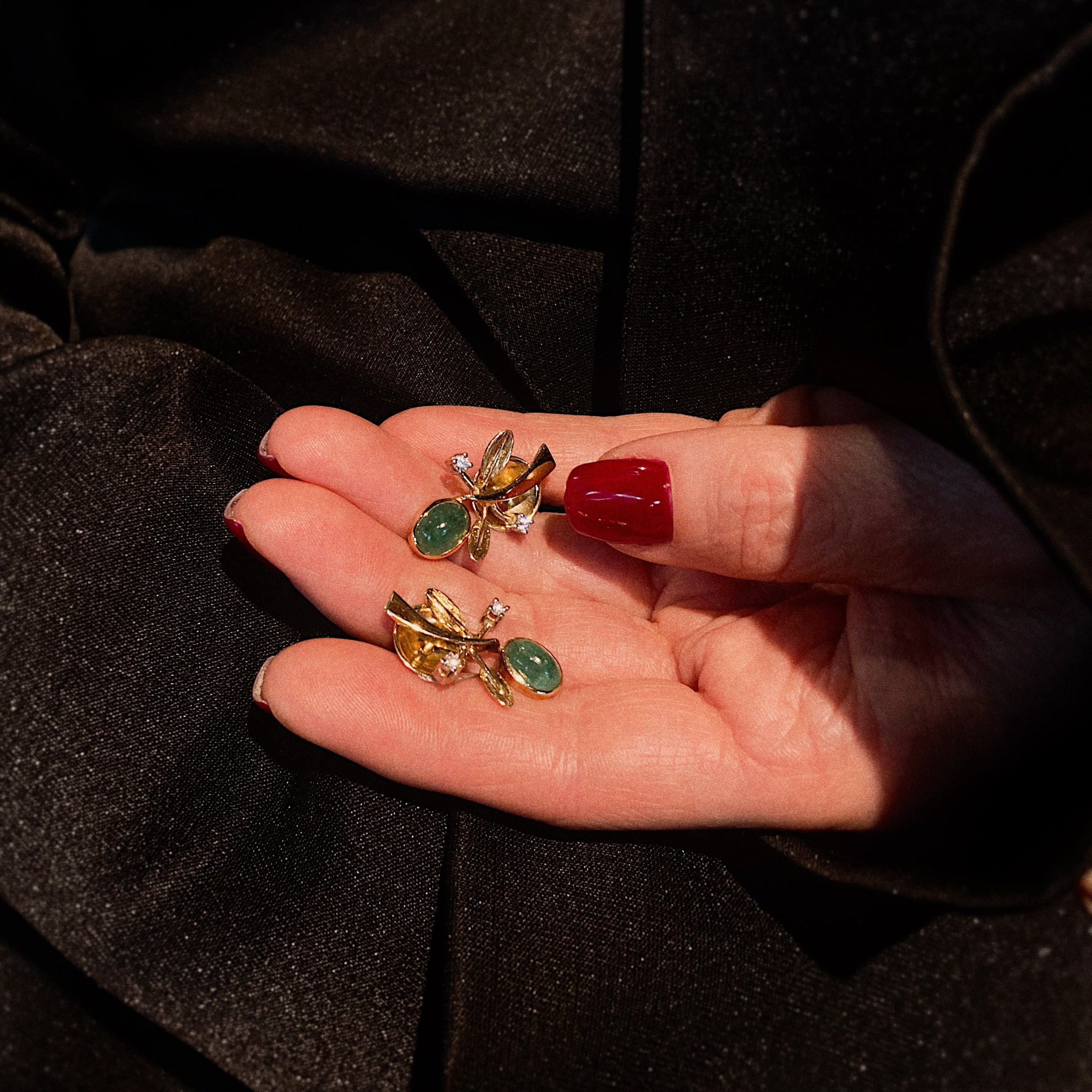Model holding the vintage Buchwald gold earrings with emeralds and diamonds.