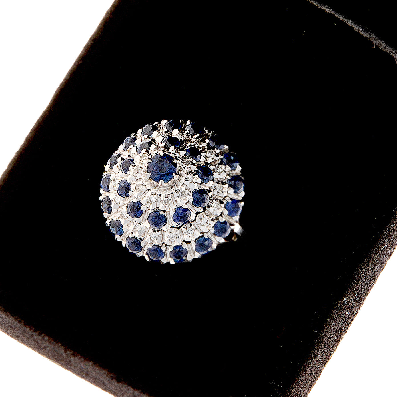 Contemporary sapphire and diamond cluster ring in white gold shown in black ring box.