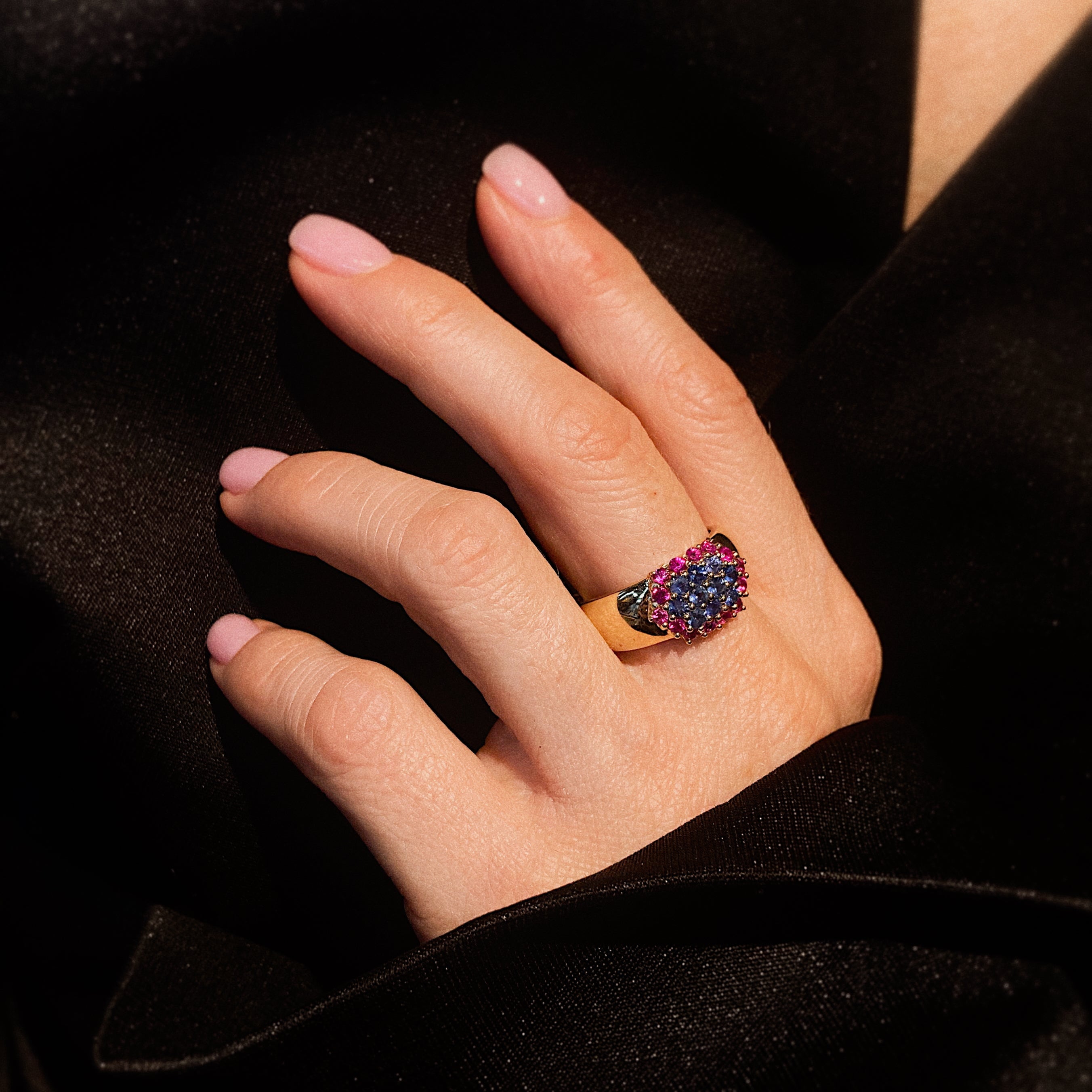 Woman wearing the contemporary gold cocktail ring with sapphire and ruby cluster.