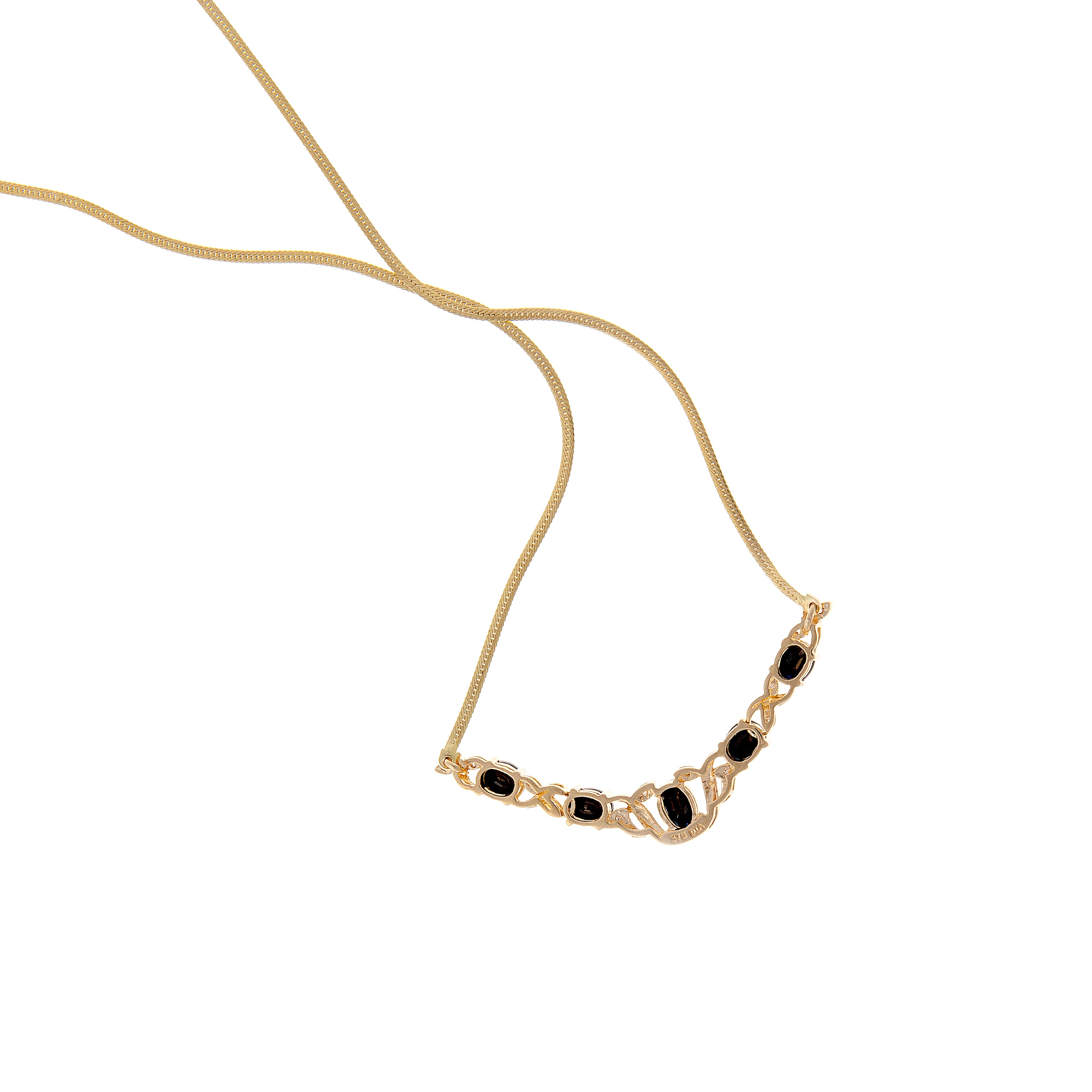 Collier vintage français en or, montrant la symétrie des pierres précieuses et la fluidité de la chaîne dans une courbe naturelle.