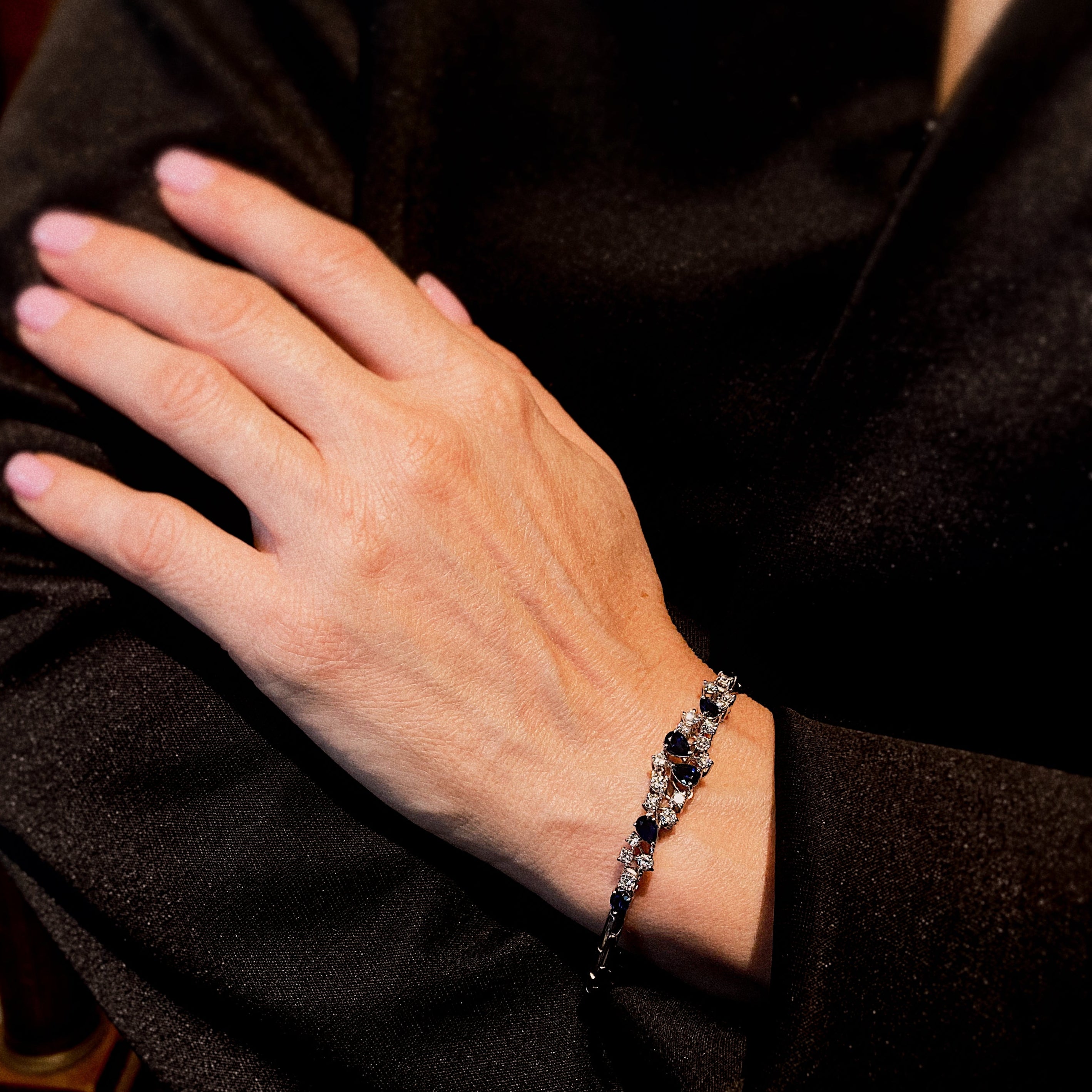 Woman wearing the contemporary vintage white gold bracelet with pear-cut sapphires and diamonds, styled for chic and elegant looks.