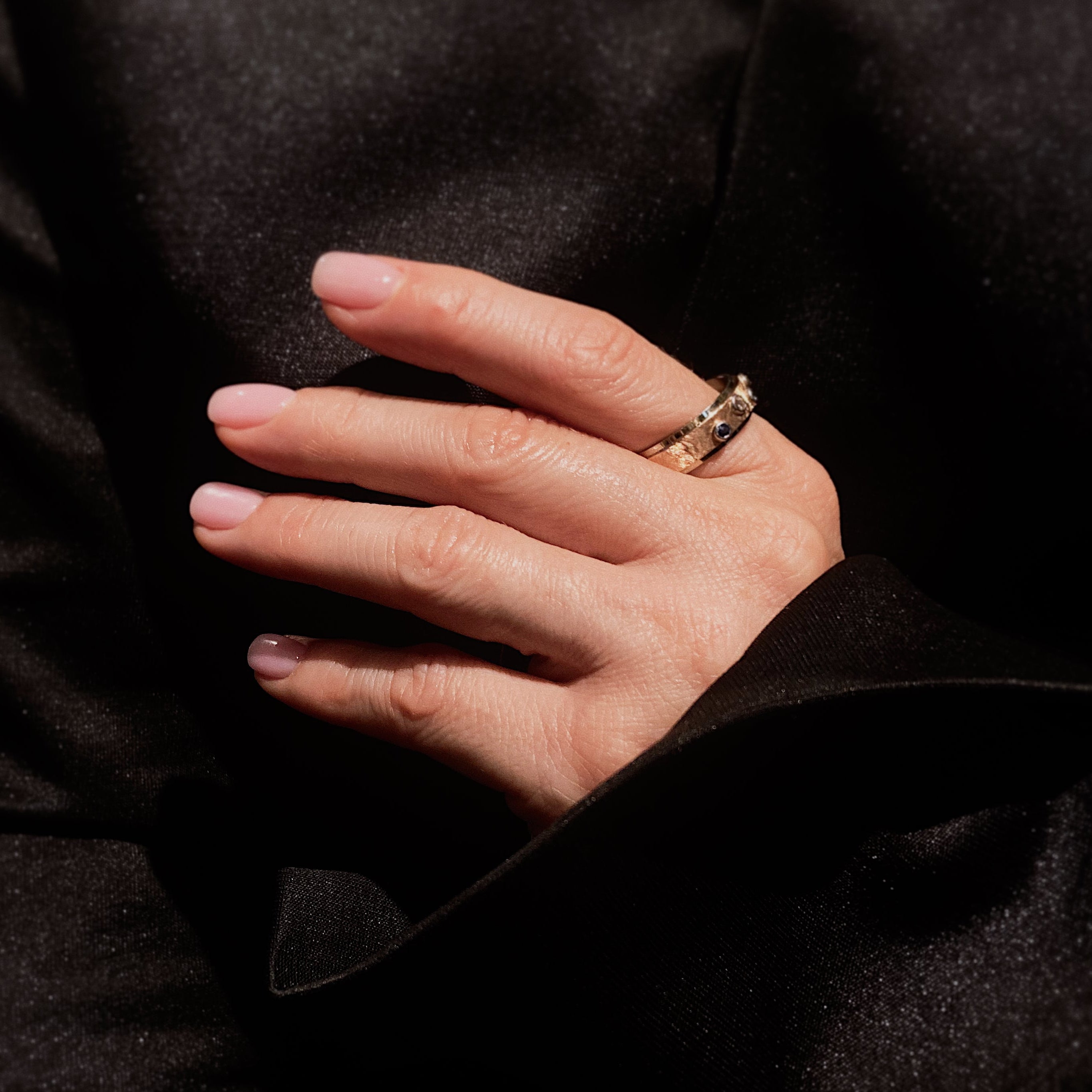 Woman wearing the contemporary vintage two-tone gold band ring with diamonds and sapphires on her hand.