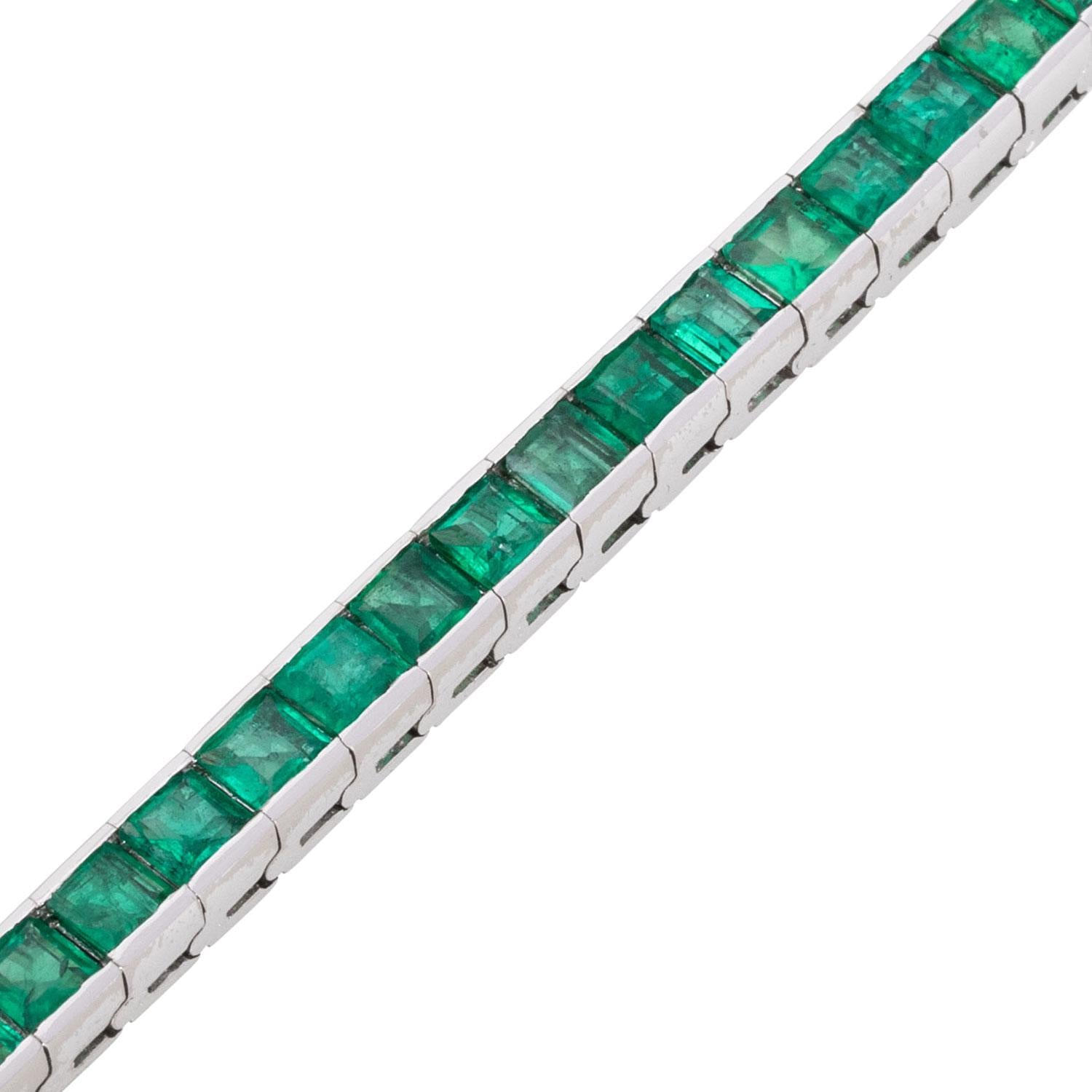 Closeup of emerald links in white gold tennis bracelet.