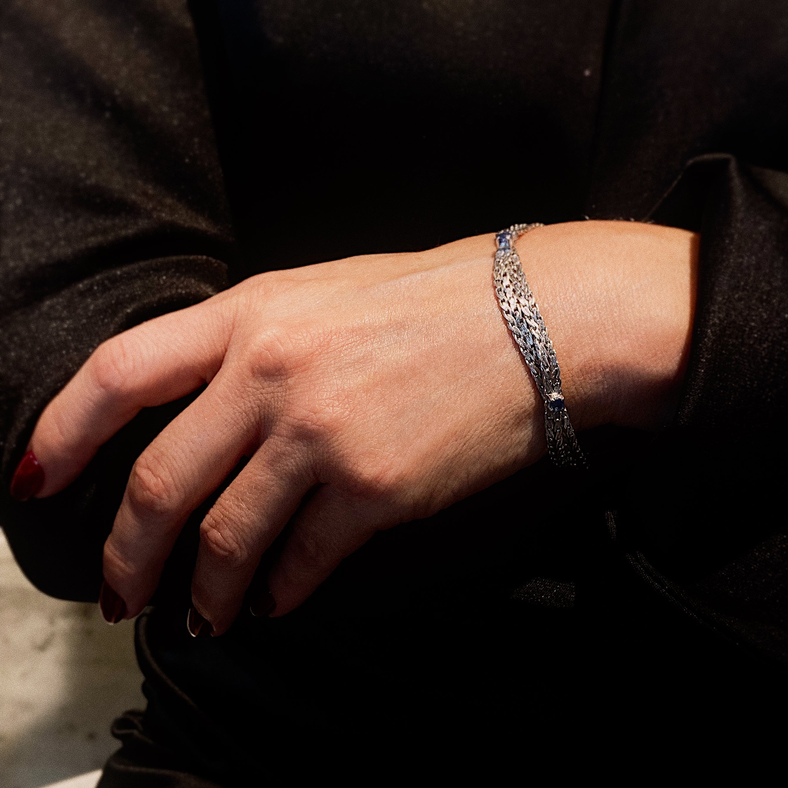 Woman model wearing the 1970s Retro revival vintage white gold bracelet with woven design and round sapphires.