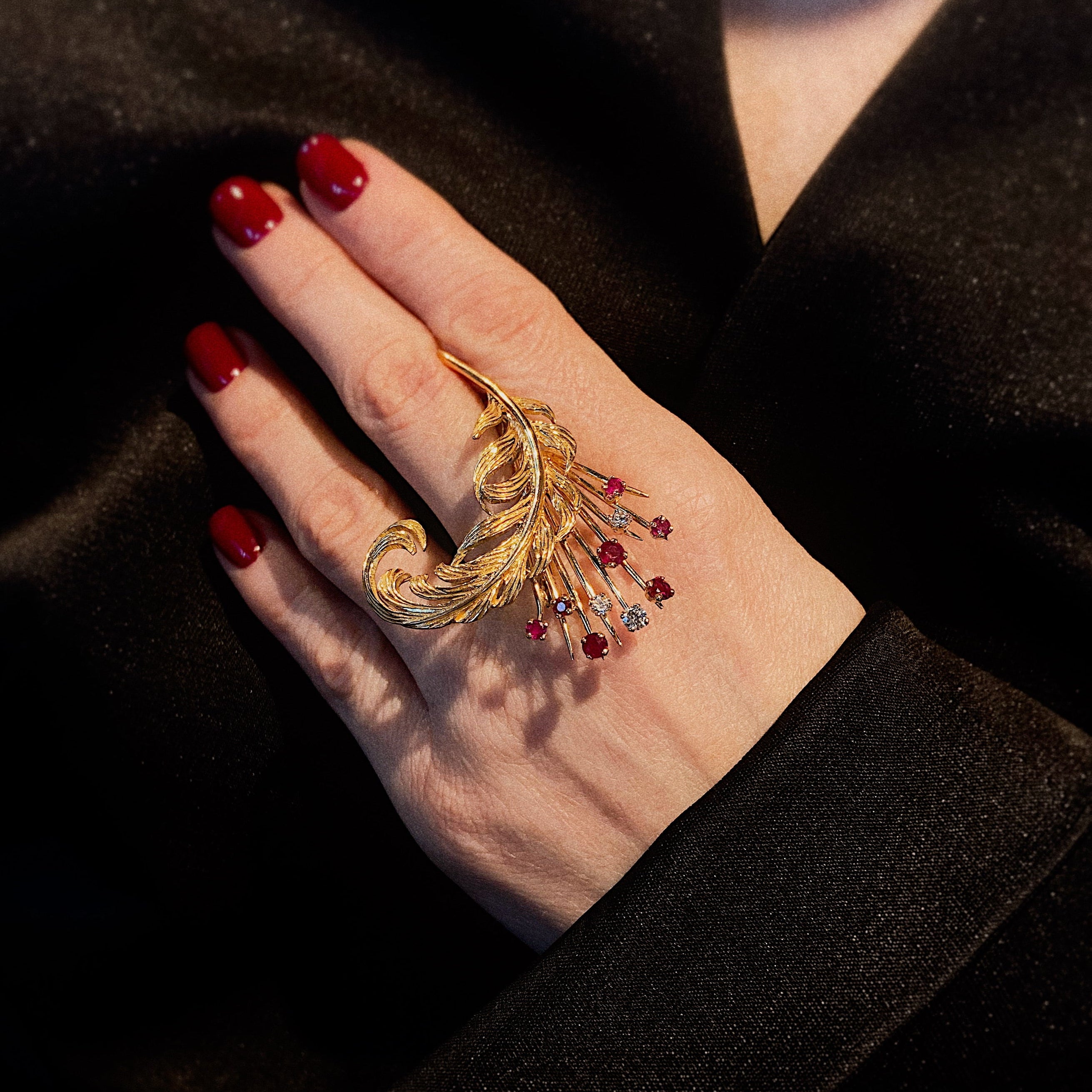 Model holding the vintage gold feather brooch with diamonds and rubies.