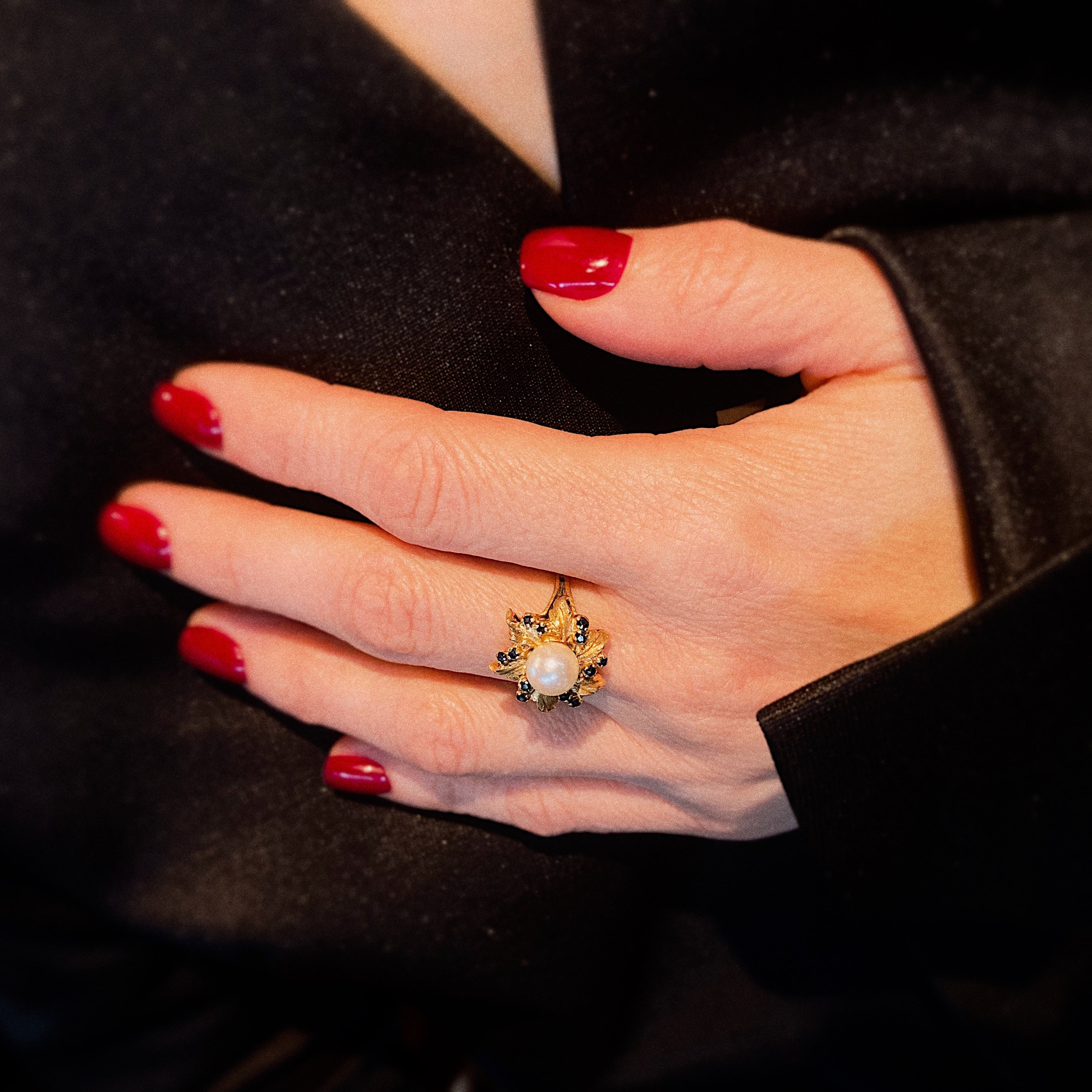 Model wearing the mid-century gold cocktail ring with pearl and sapphires in a floral design.