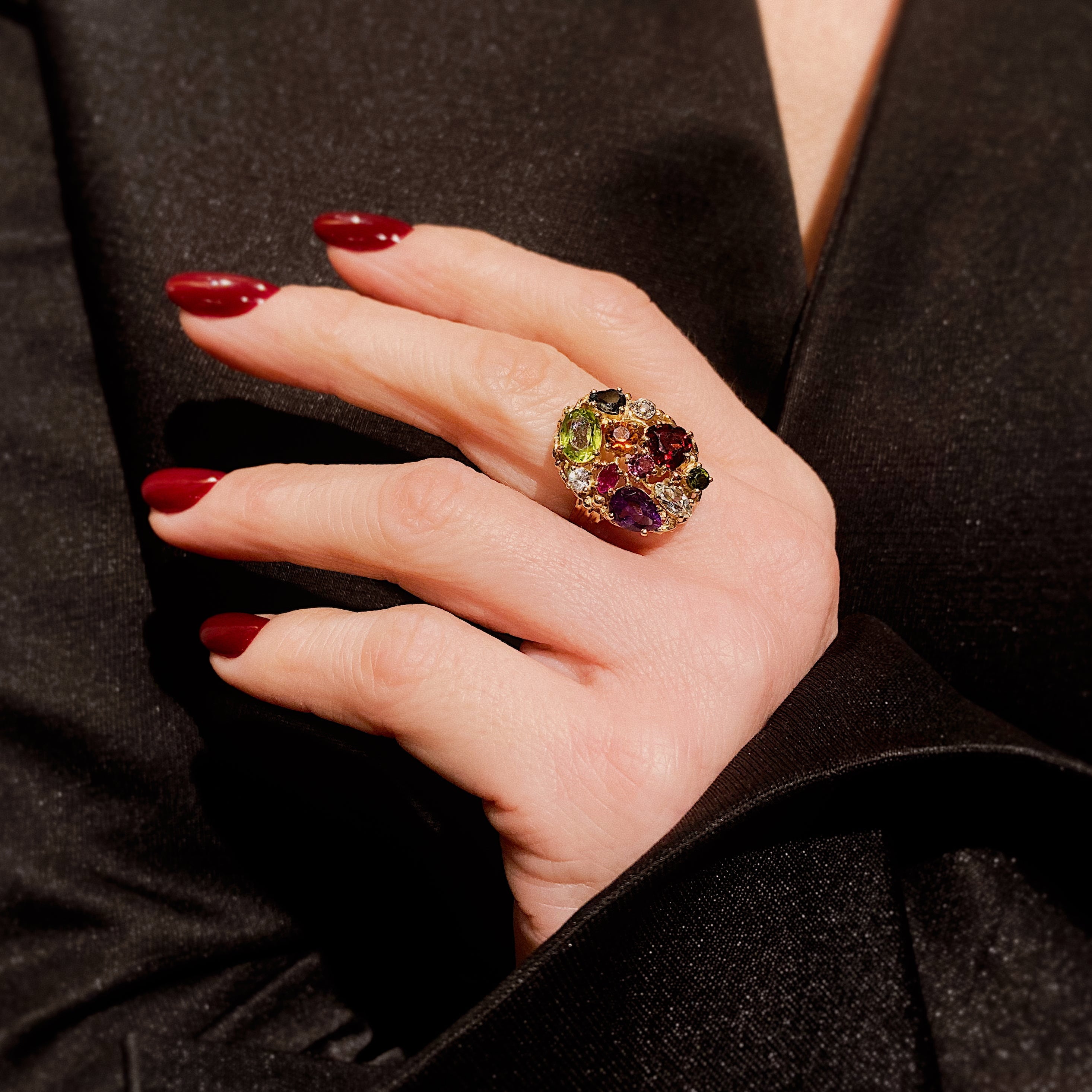 Hand einer Frau, die den Mid-Century Harlekin-Cocktailring aus Gold mit mehreren Edelsteinen trägt.