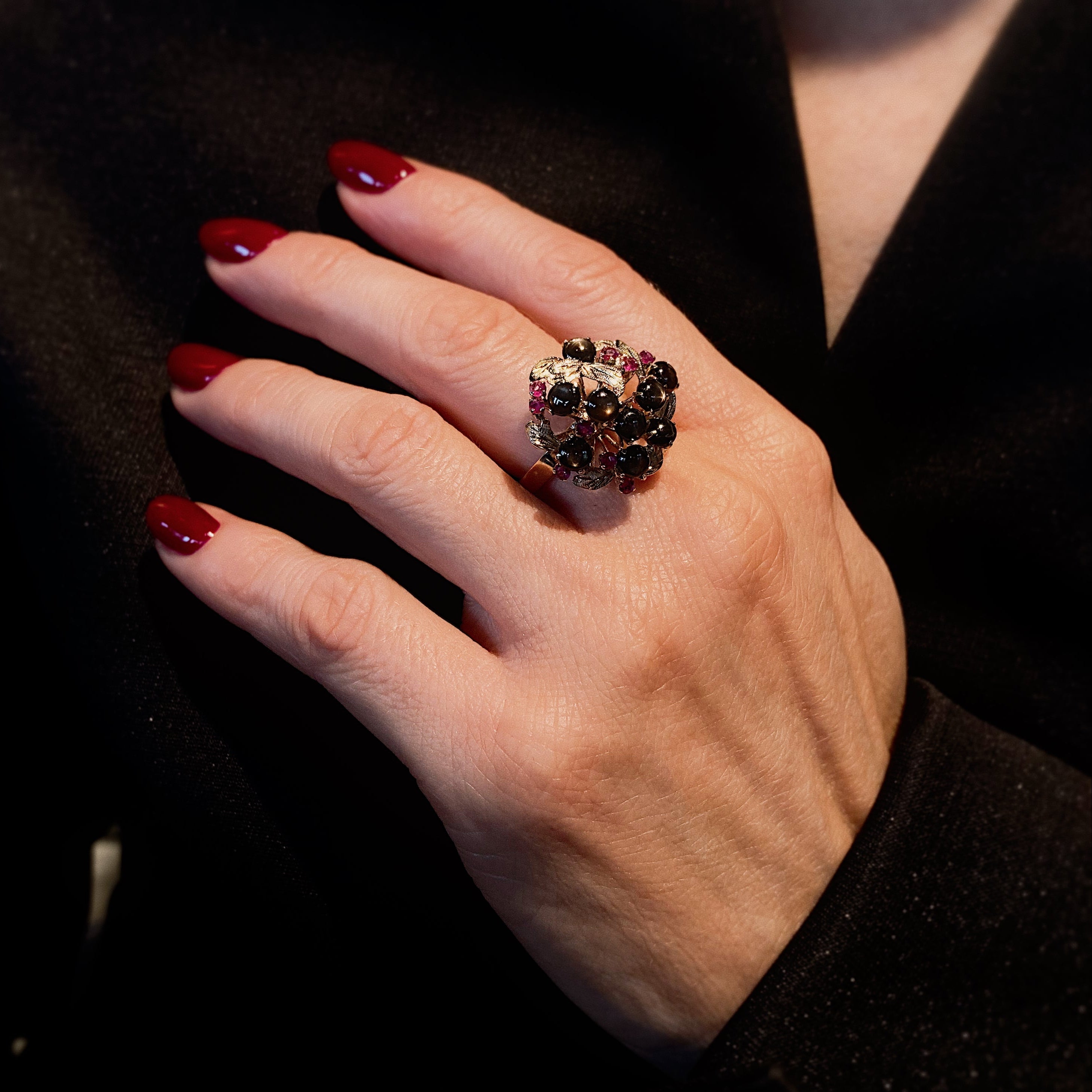 Woman wearing the Mid-Century gold star sapphire and ruby cluster cocktail ring.
