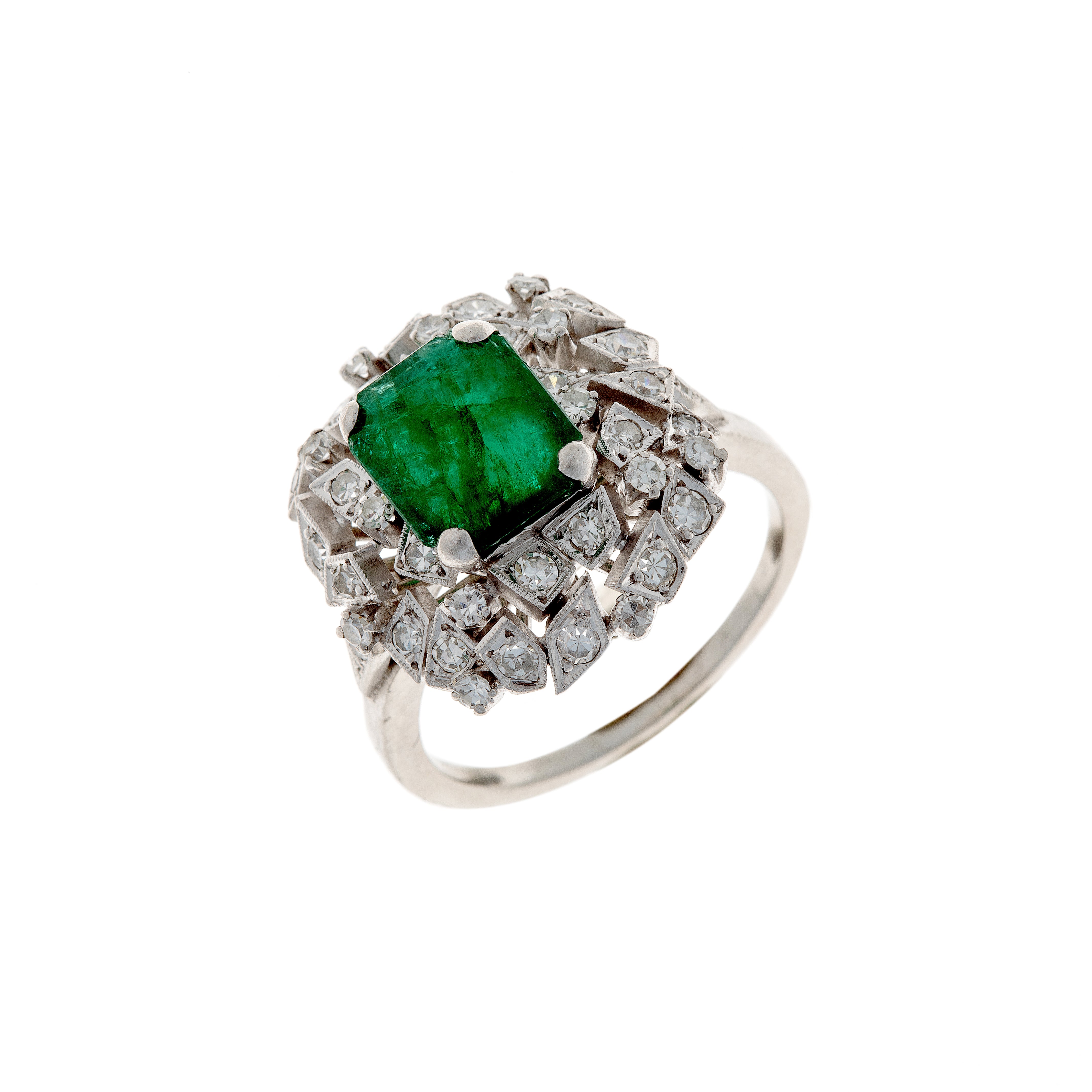 Angled perspective of a 1950s–70s platinum ring showcasing an emerald centerpiece and double diamond halo setting.
