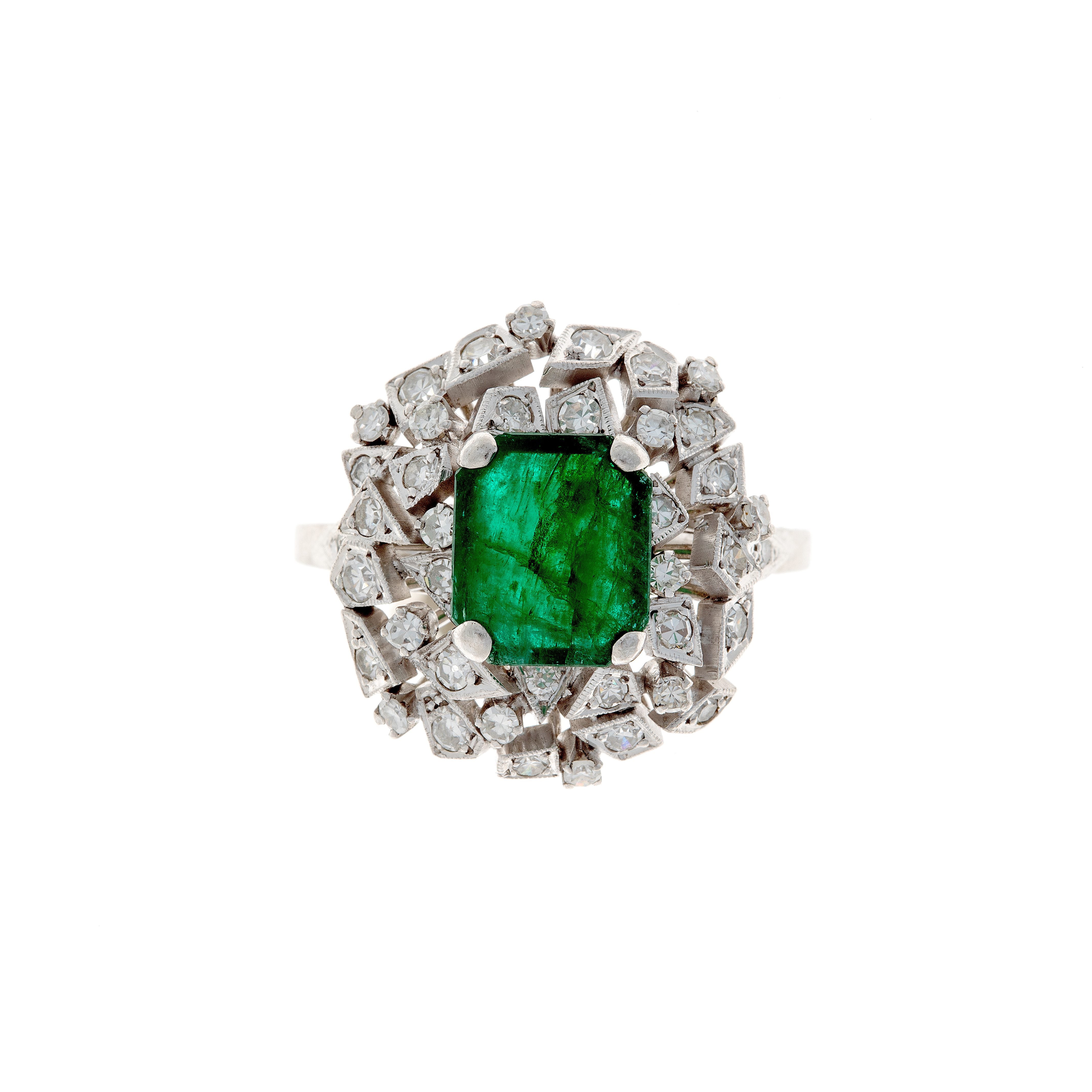 Vintage mid-century platinum cocktail ring featuring a vibrant emerald surrounded by two halos of  diamonds.