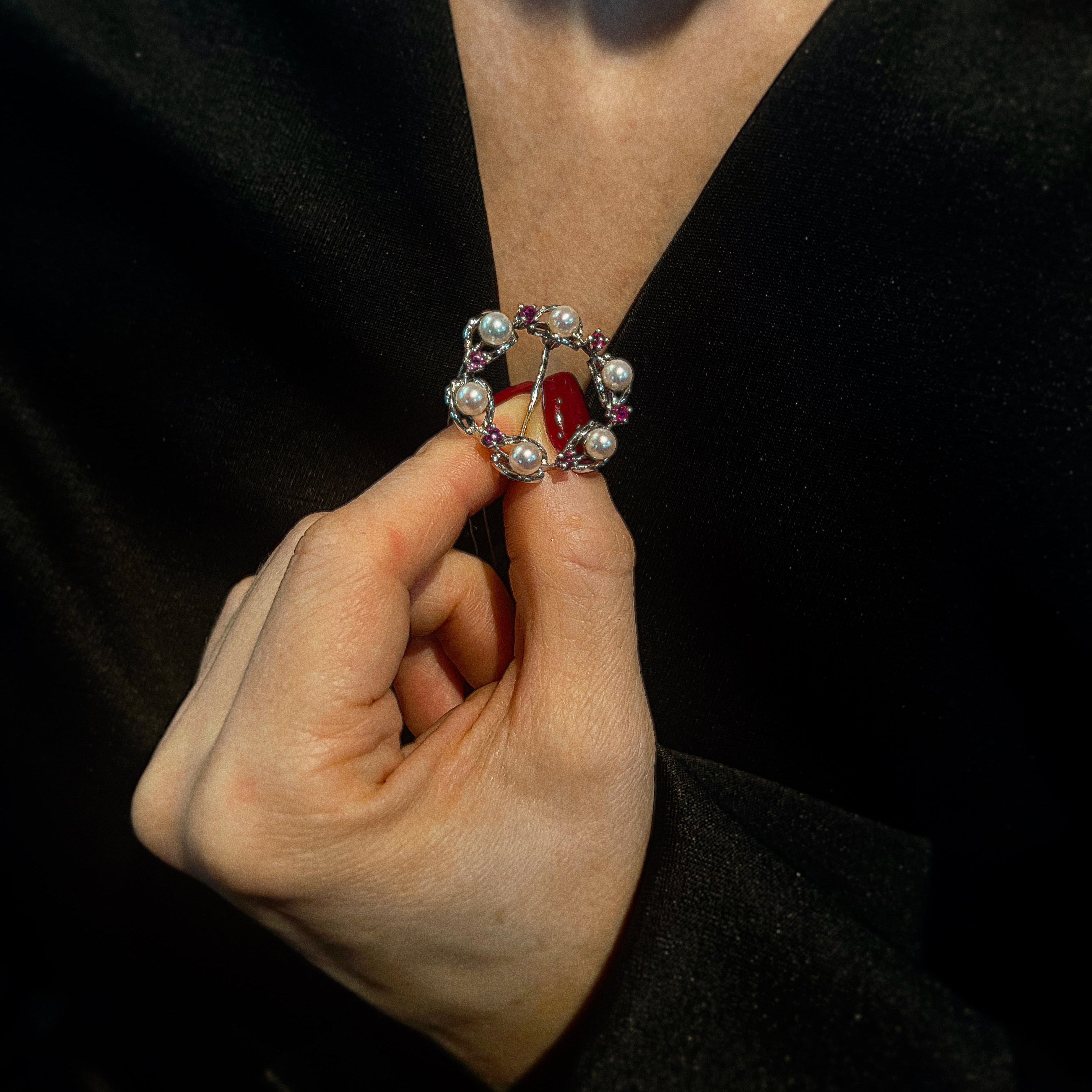 Model holding the mid-century white gold brooch with pearls and rubies.
