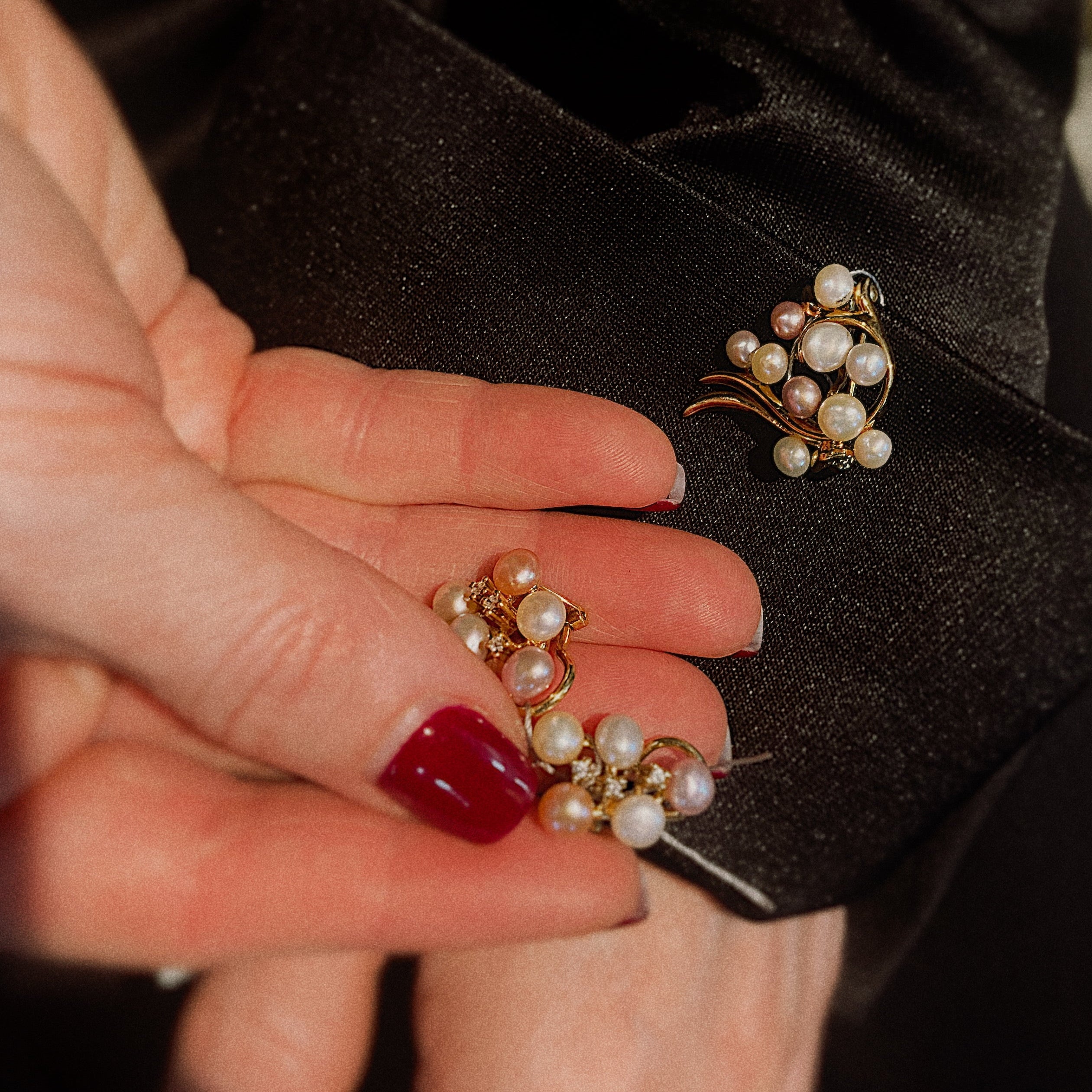 Model holding the vintage gold earrings with freshwater pearl clusters.