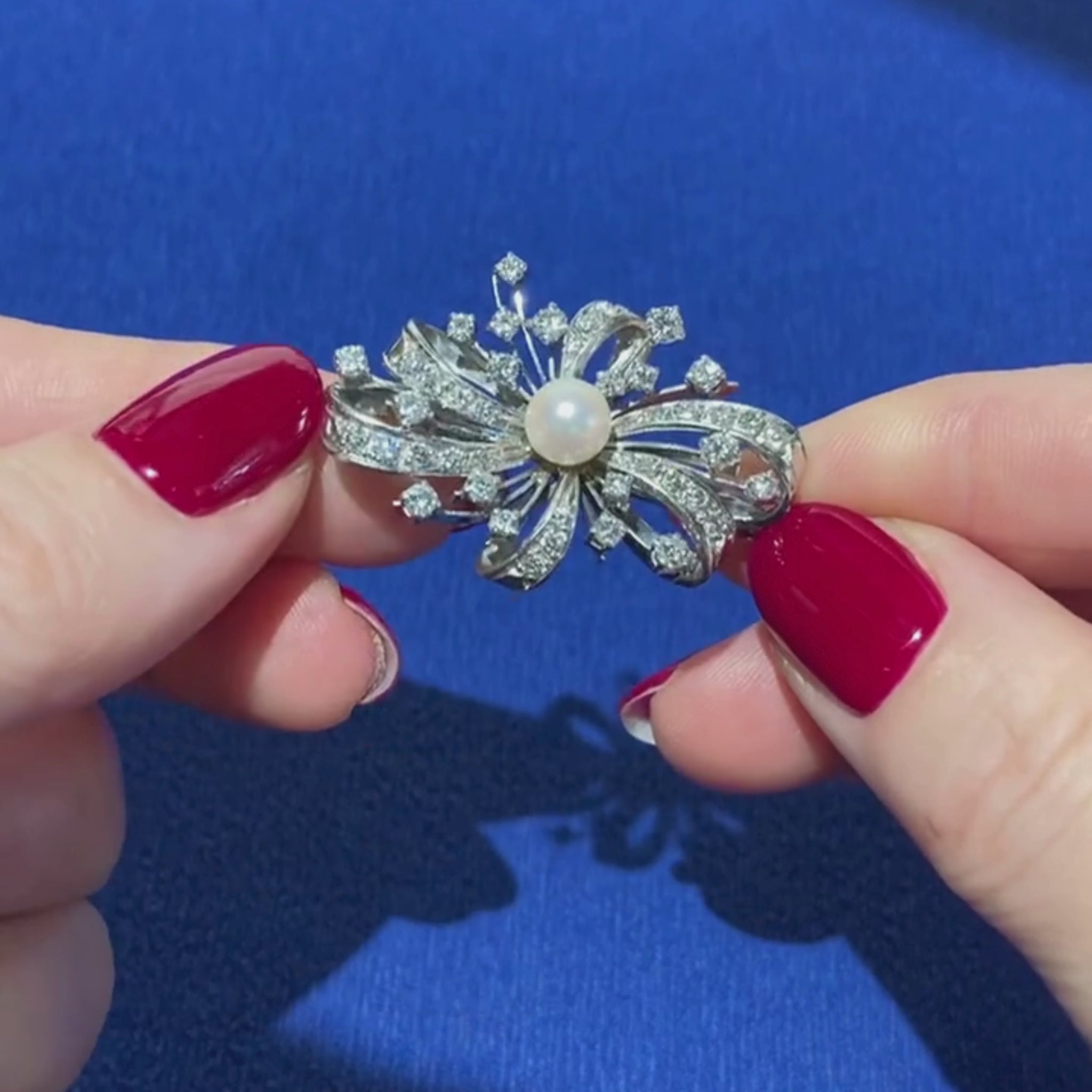 Closeup video of a woman model showcasing the Mid-Century diamond and pearl white gold bow brooch pendant.
