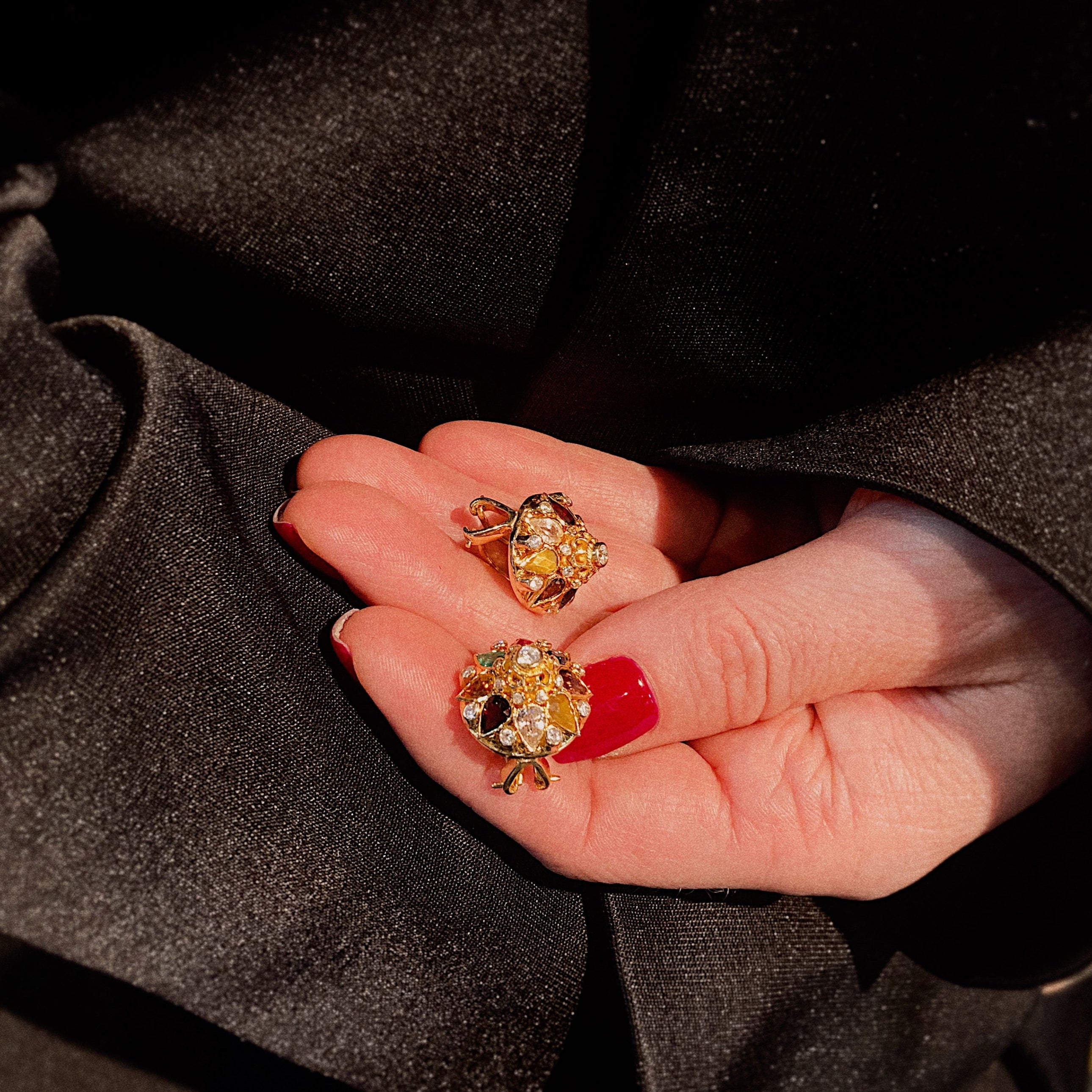 Model holding the vintage gold colored gemstone cluster earrings.