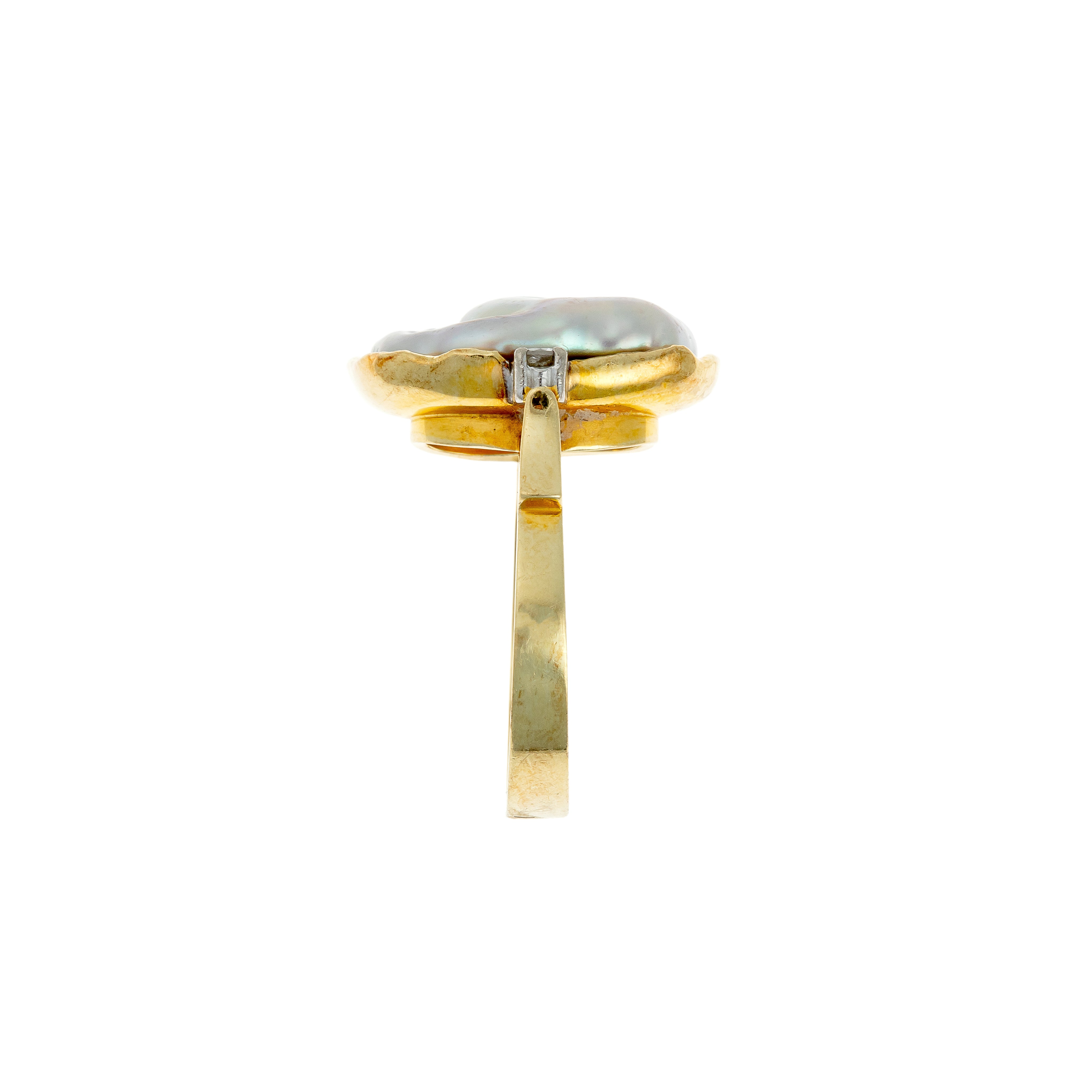 Side view revealing the raised baroque pearl and textured bezel of the gold ring.