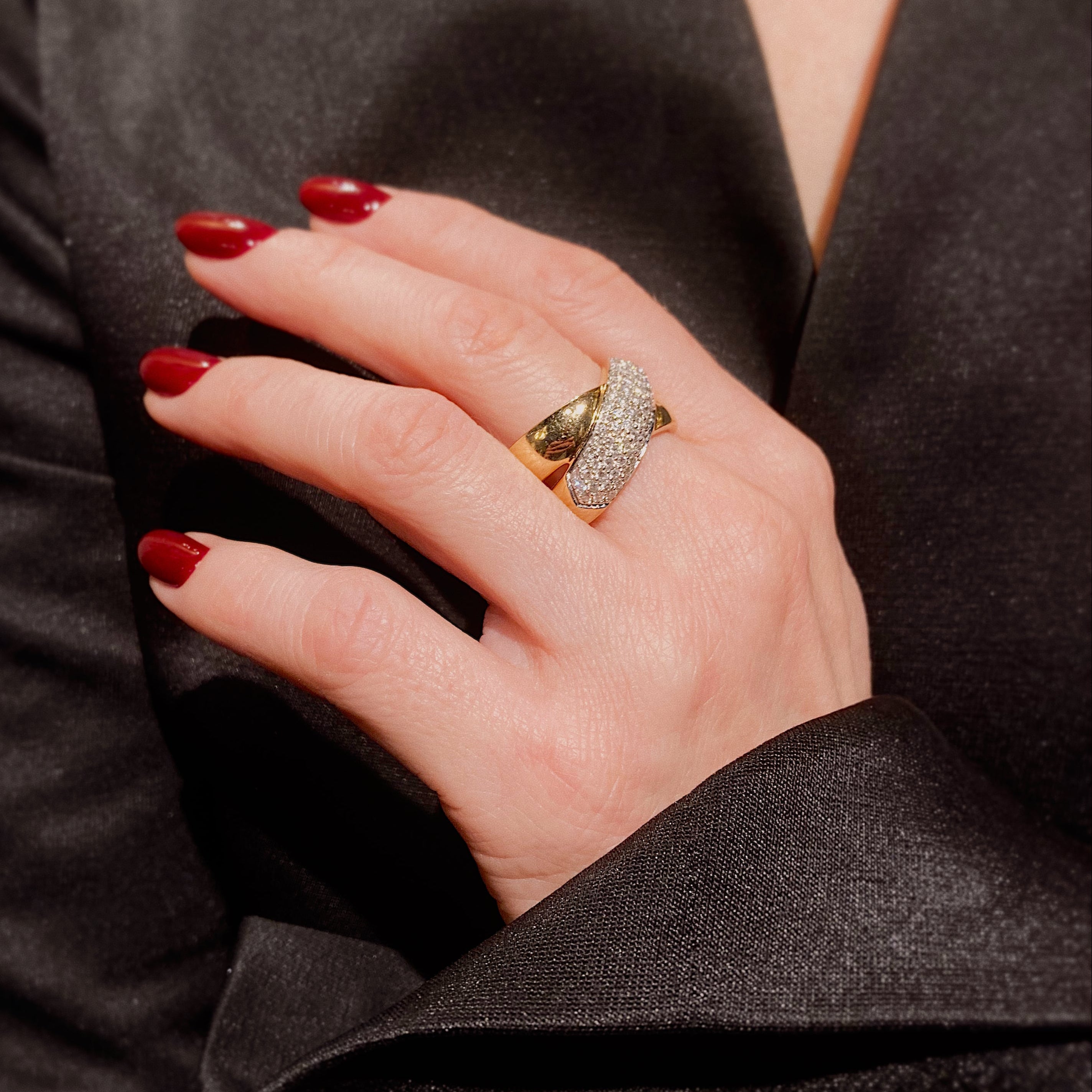 Woman's hand wearing the vintage Christ two-tone gold pavé diamond crossover ring.