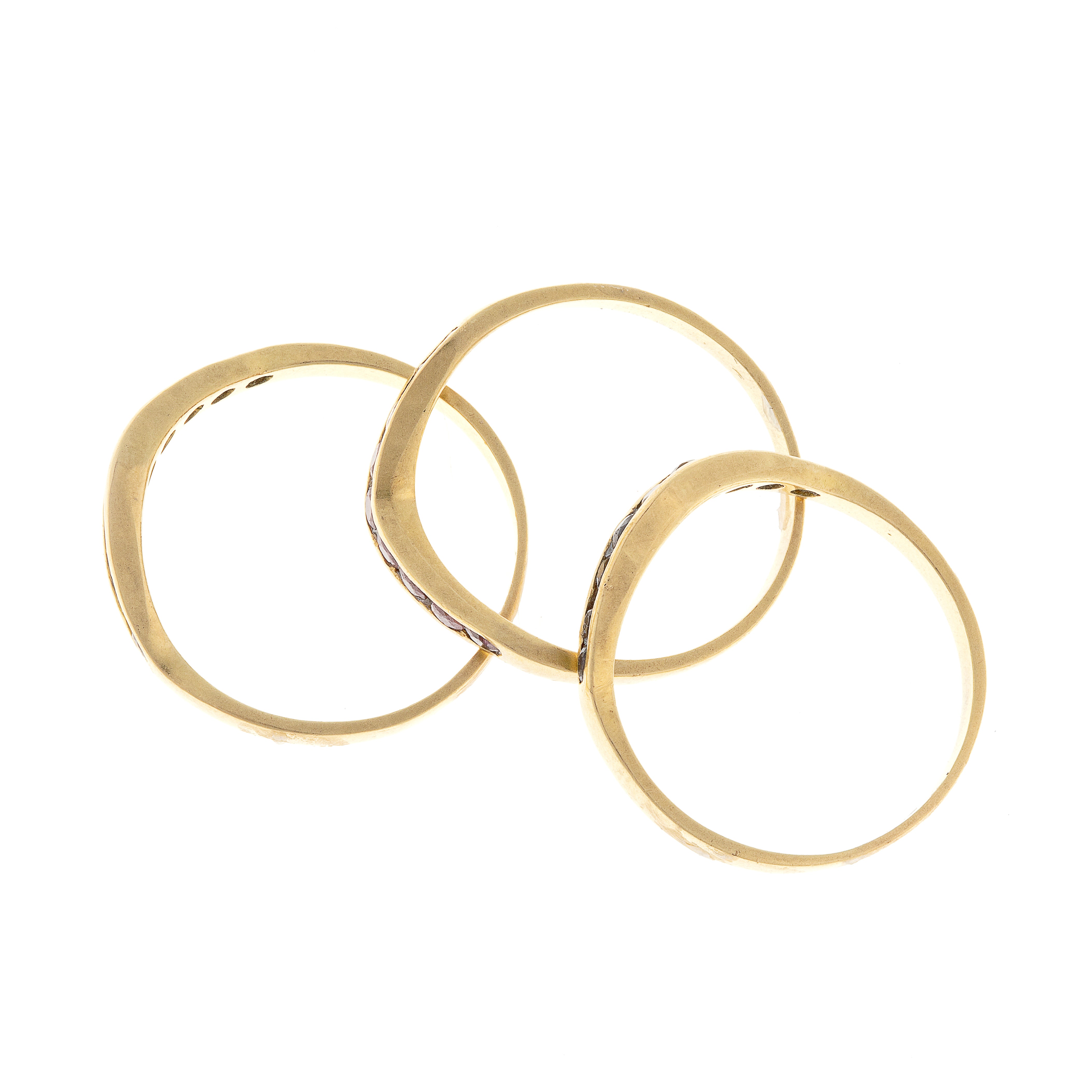 Disassembled view of three gold chevron rings laid flat, highlighting individual gemstone colors and band shapes.