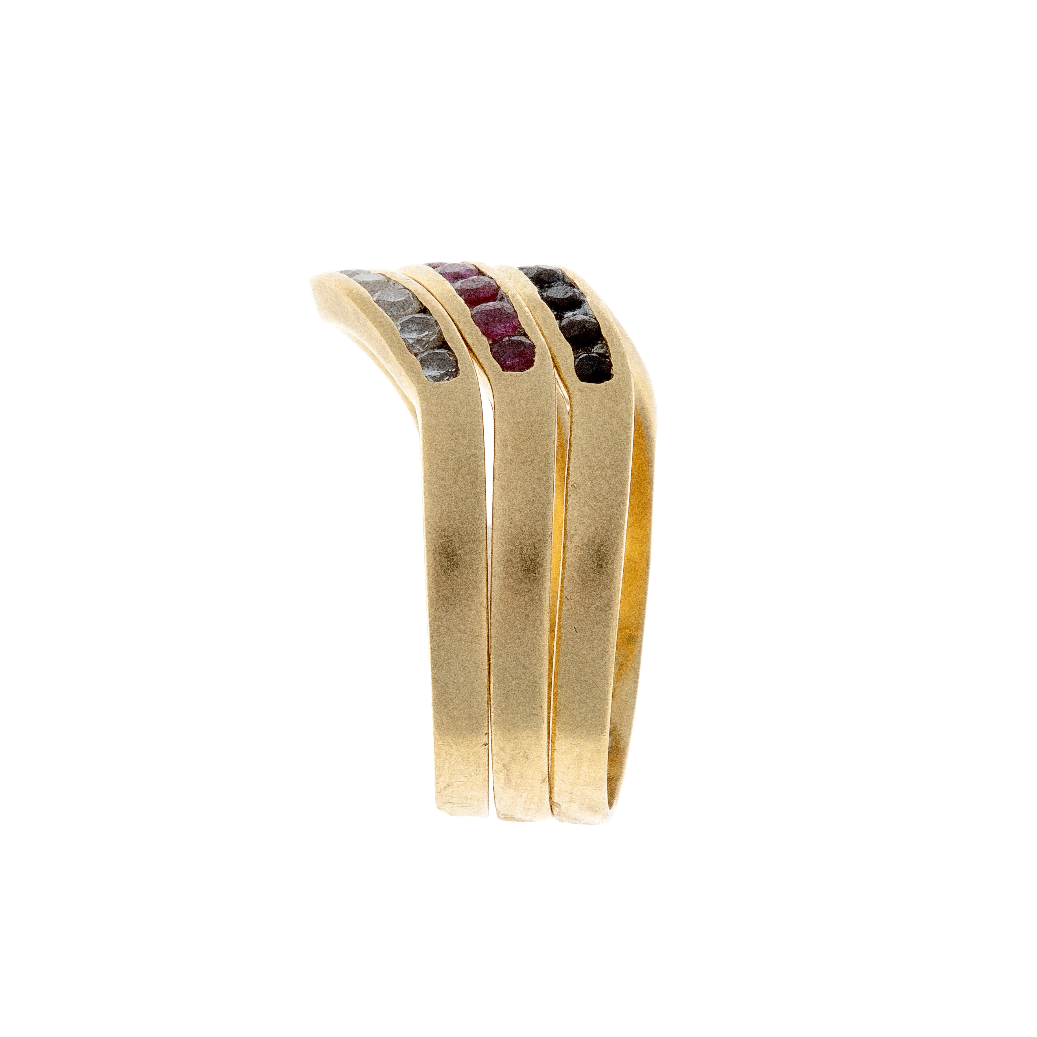 Side view of three 18K gold rings with vibrant rubies, blue sapphires, and clear sapphires in stacked formation.