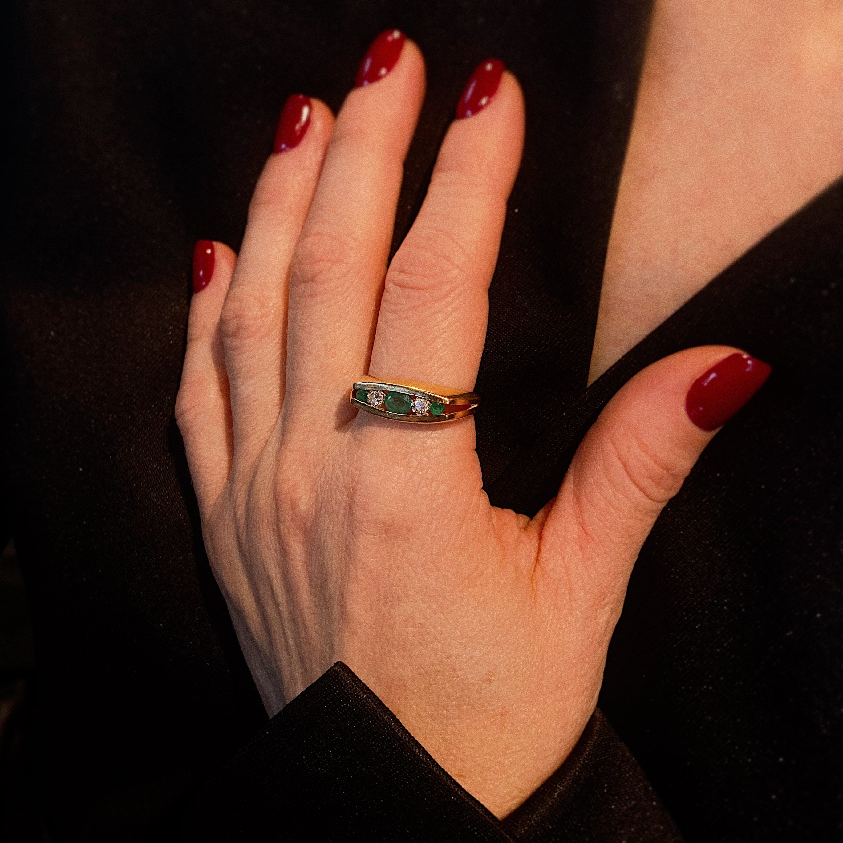 Femme portant la bague cocktail vintage en or à rangées de diamants et d'émeraudes.