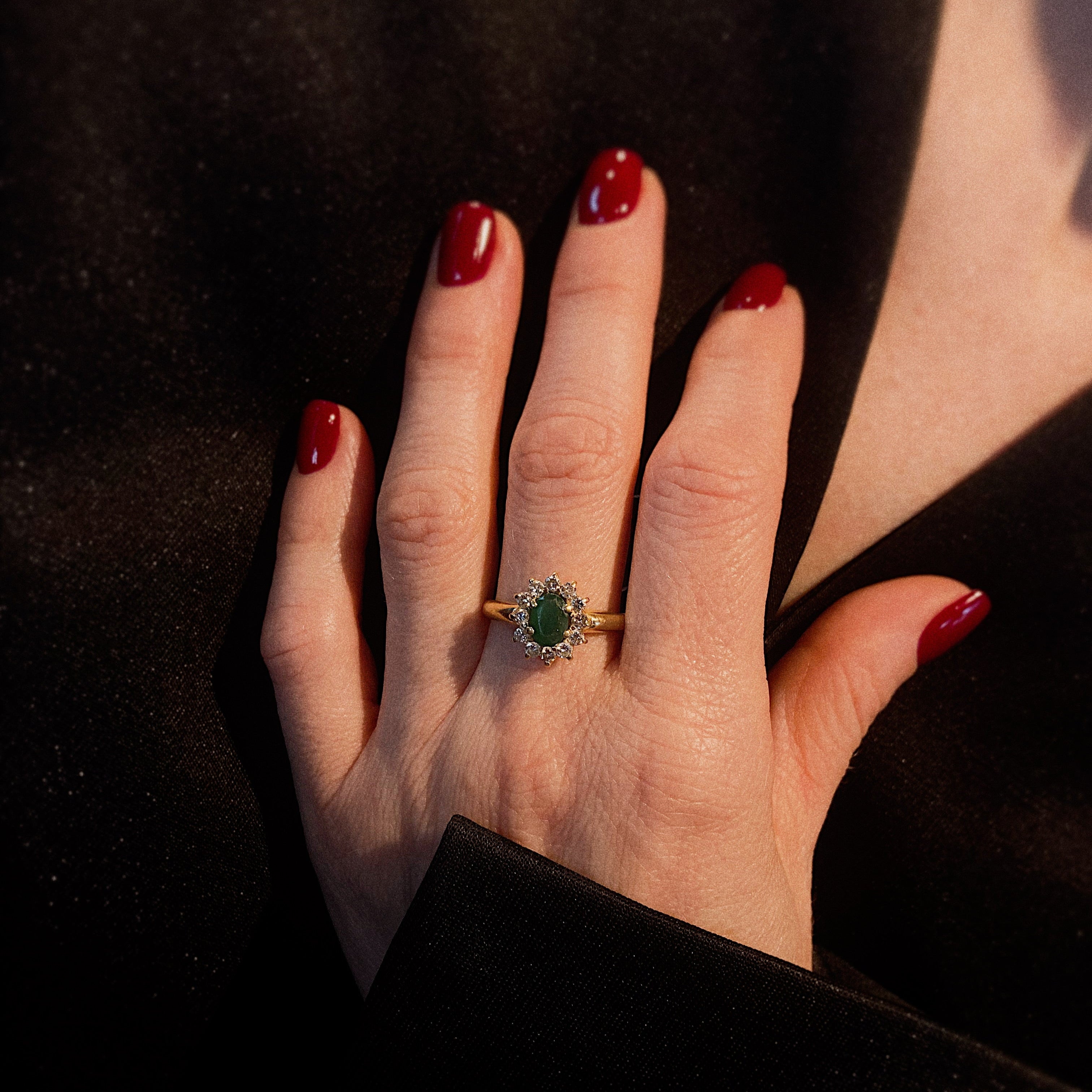 Frau, die den Vintage-Gold-Smaragd- und Diamant-Halo-Pompadour-Cocktailring trägt.