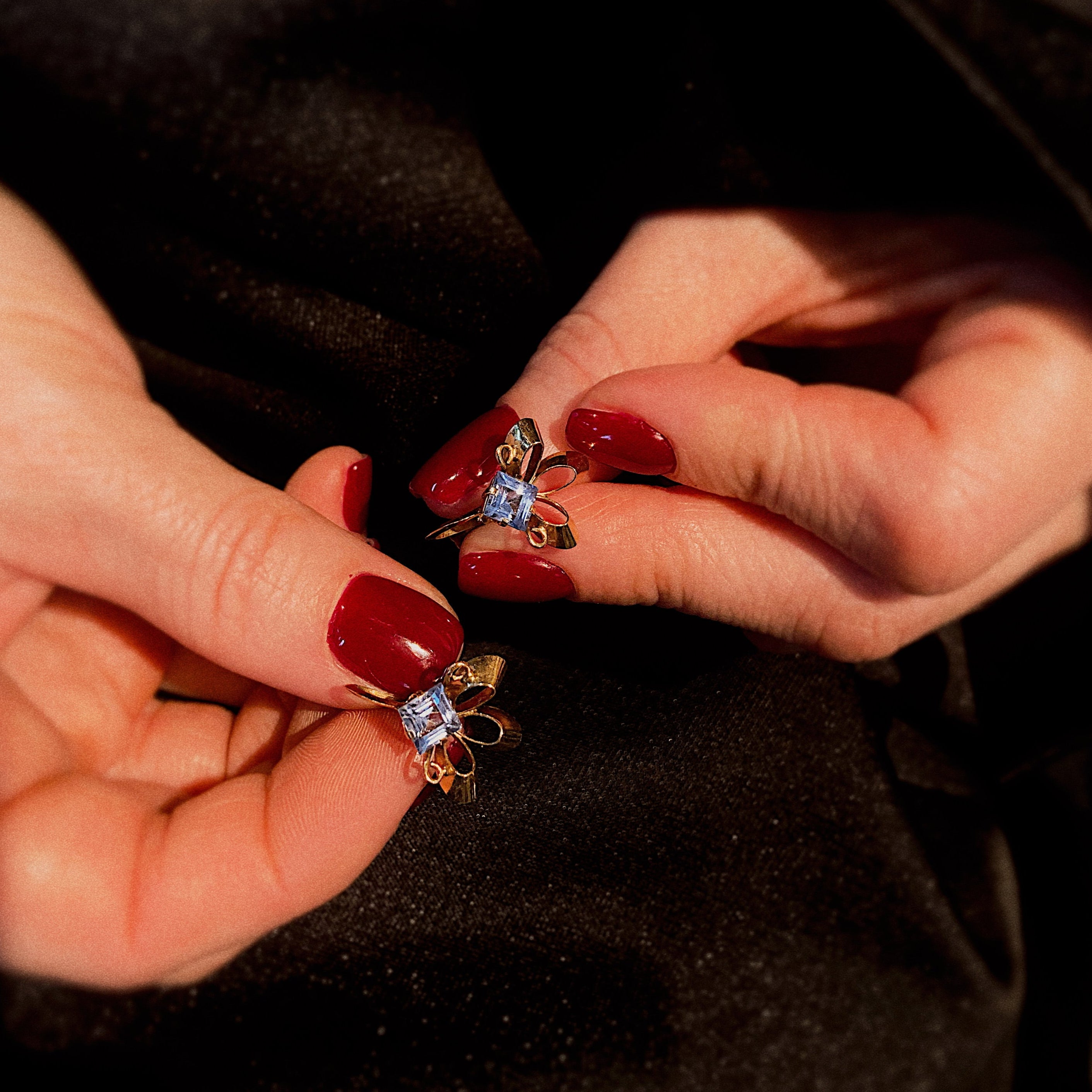 Model holding the vintage gold fleur-de-lis earrings with blue spinels.