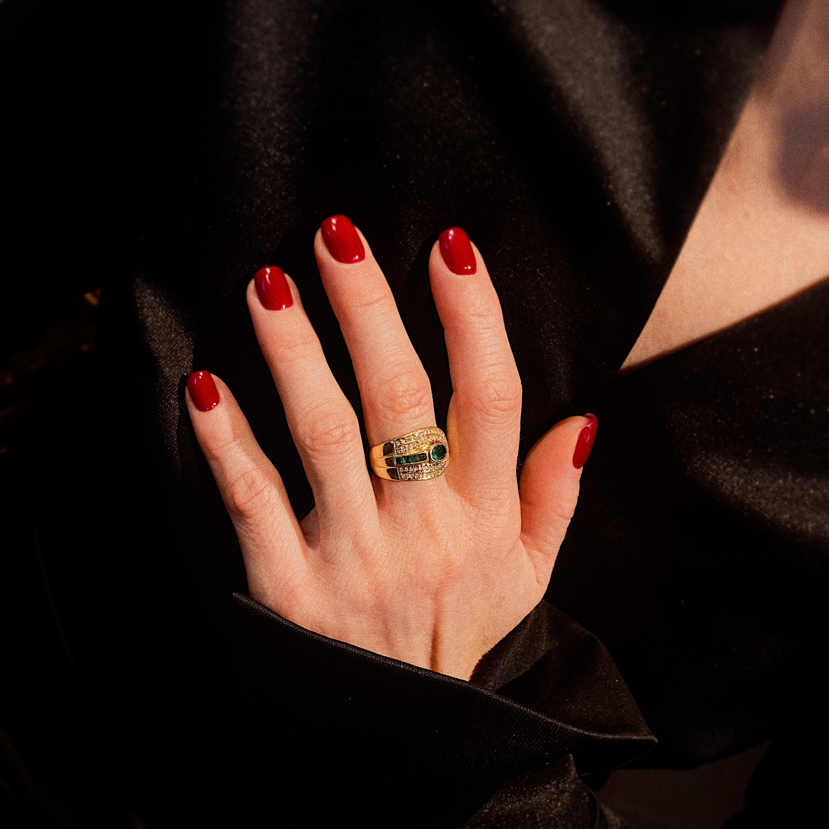 Model wearing the 1980s gold cocktail ring with emeralds and diamonds.