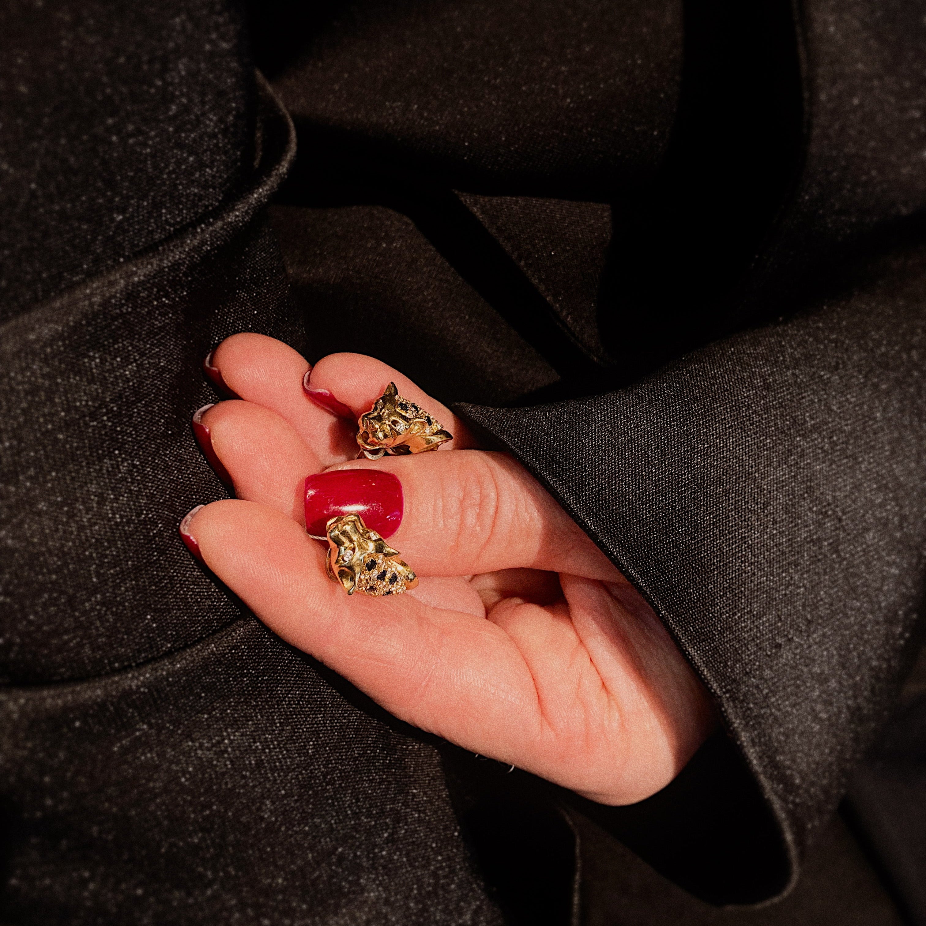 Femme tenant les boucles d'oreilles léopard vintage en or avec saphirs et diamants.