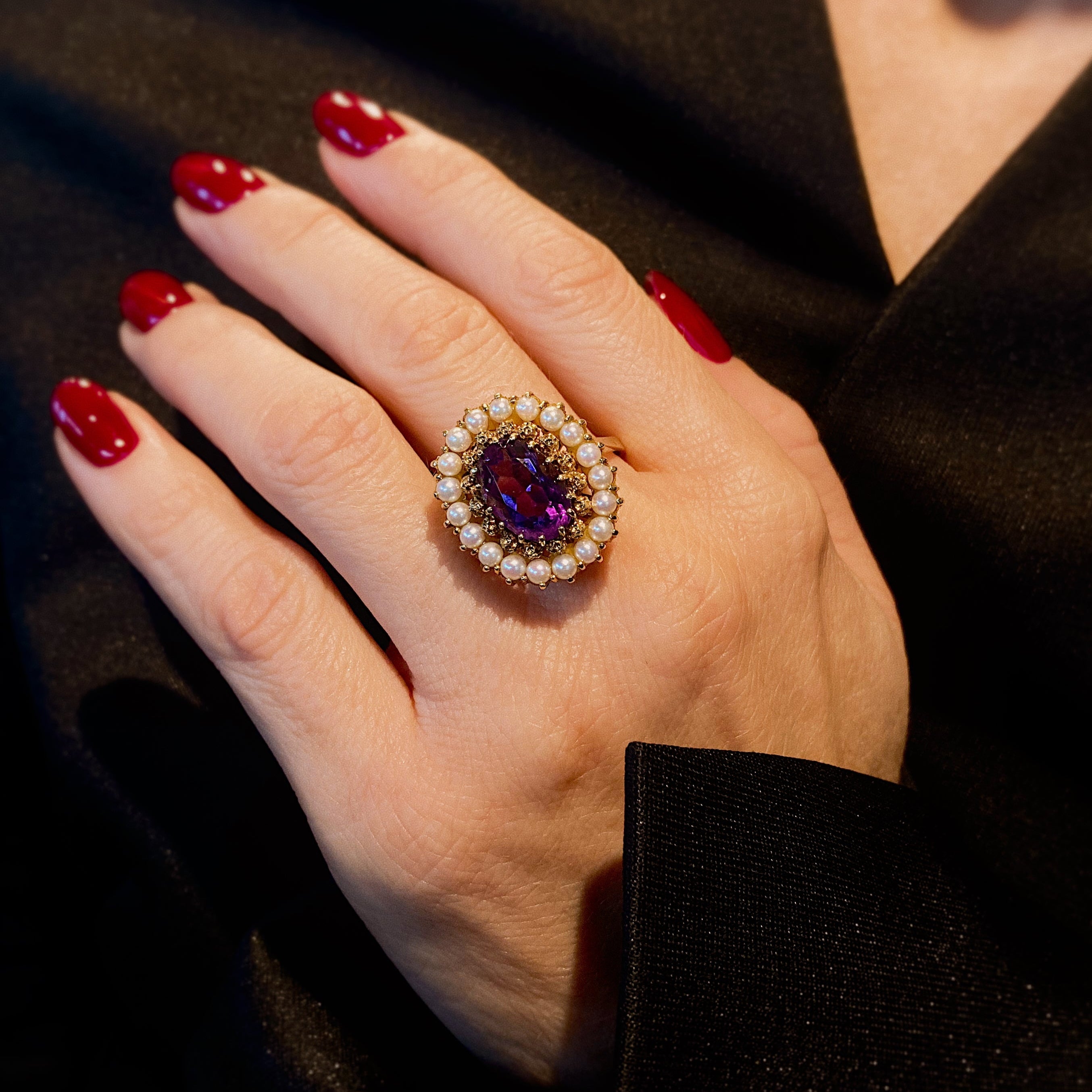 Woman model wearing the vintage mid-century gold cocktail ring with amethyst and pearl halo.