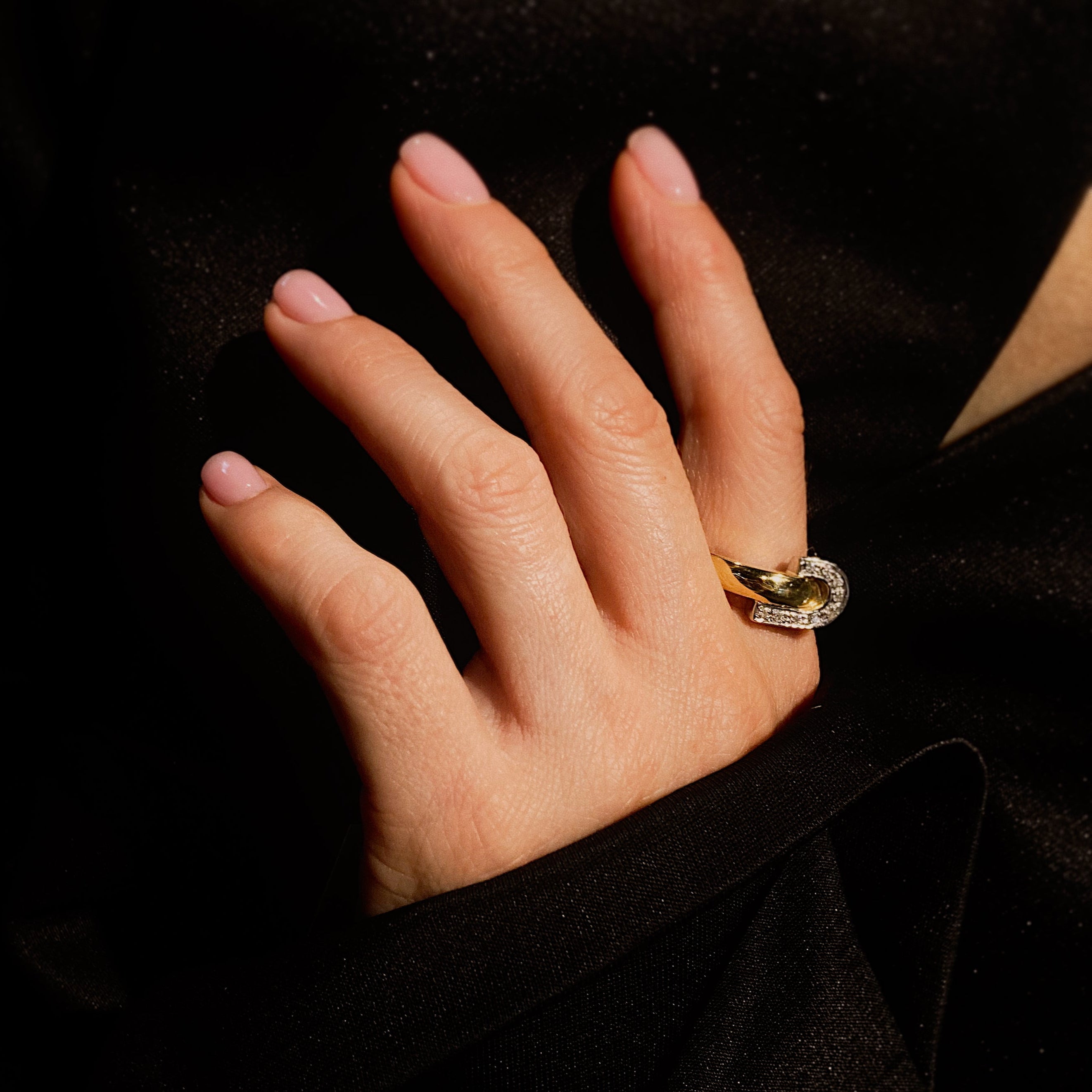 Woman model's hand wearing the retro vintage two-tone sculptural cocktail ring in yellow and white gold with diamond accents.