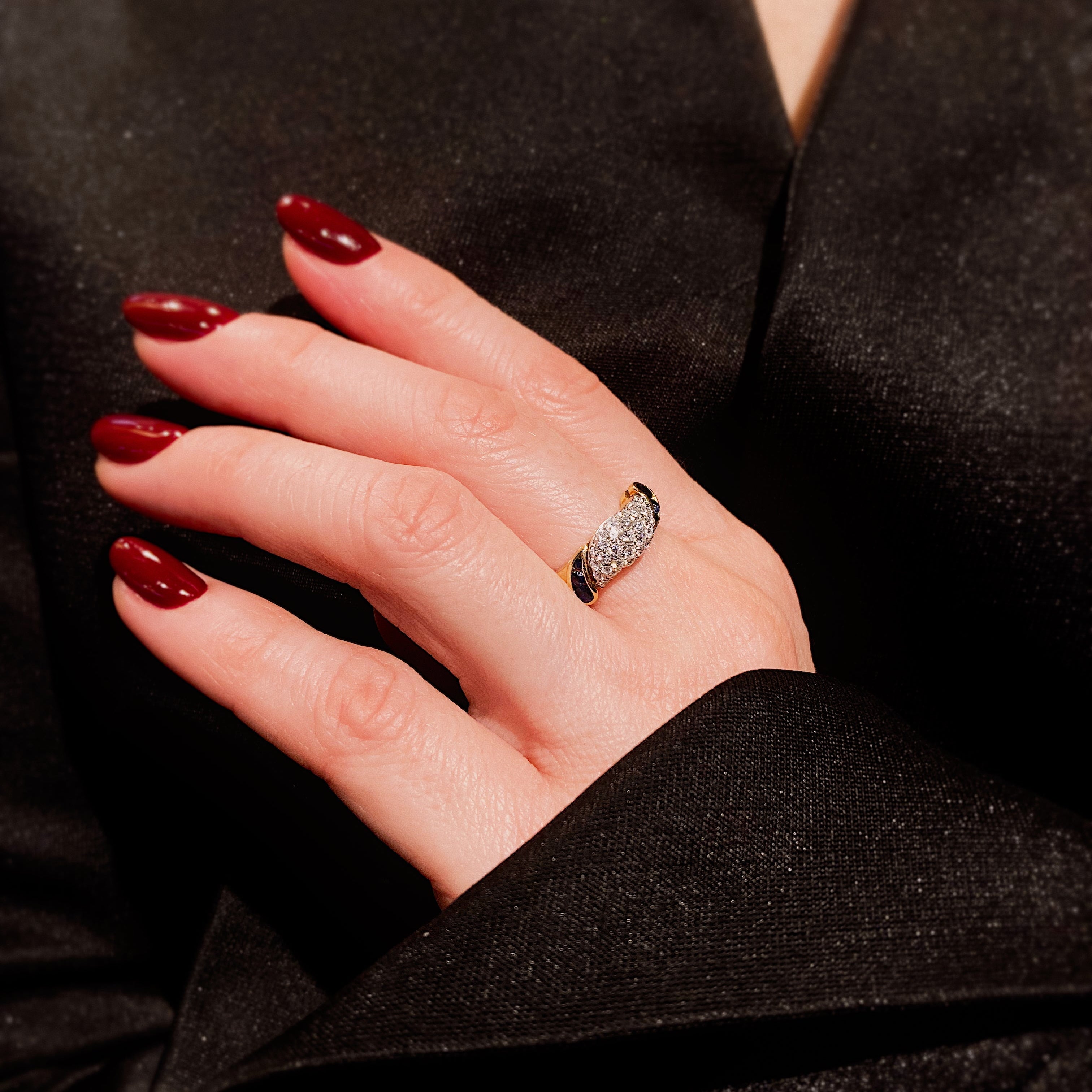 Woman's hand wearing the vintage two-tone gold diamond and sapphire domed cocktail ring.
