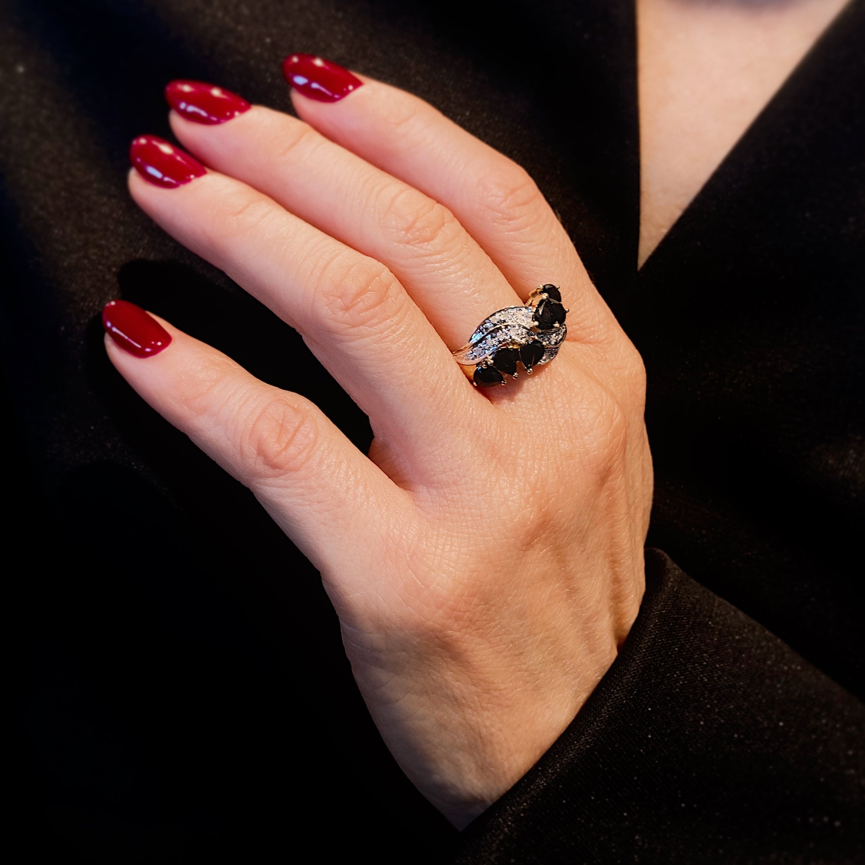 Woman wearing the vintage two-tone gold pear-cut sapphire and diamond cascade ring.