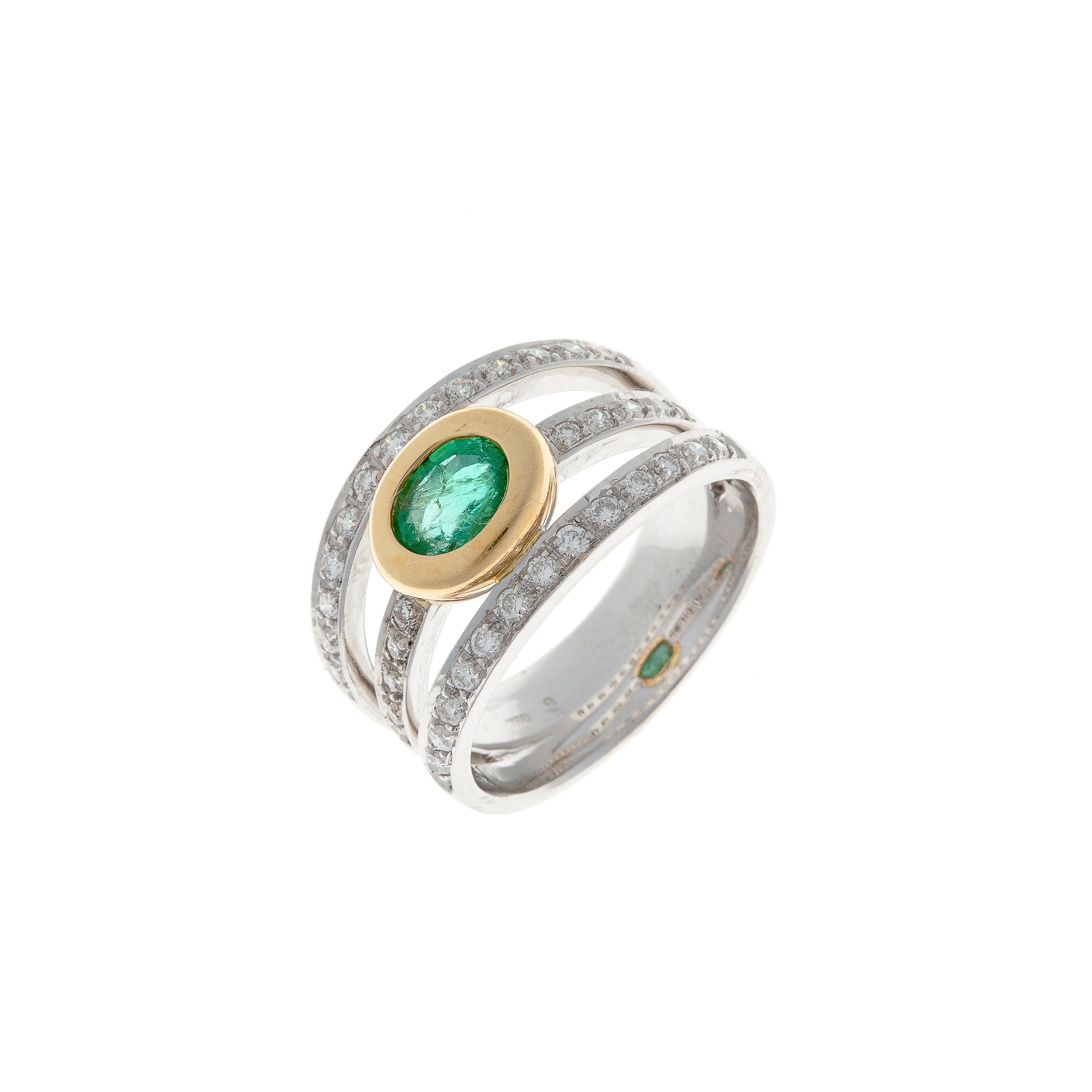 Angled view of vintage white and yellow gold ring showing emerald bezel and surrounding diamonds.