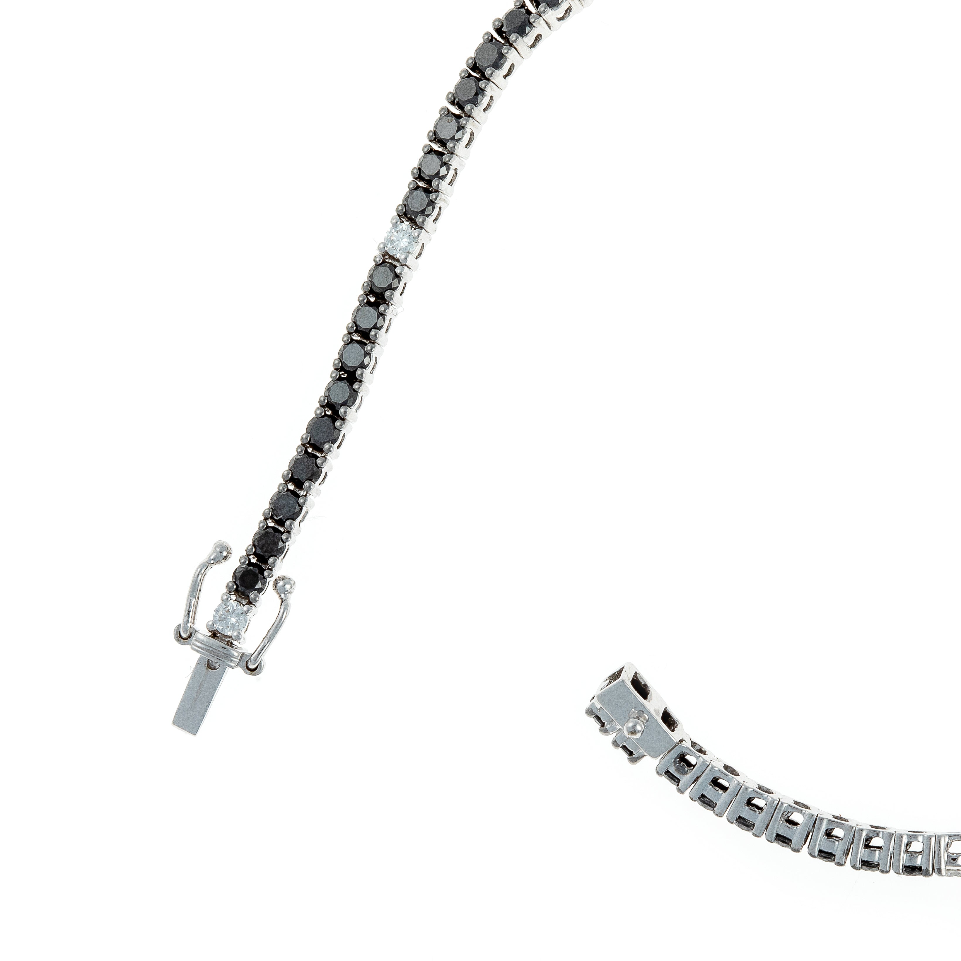 Detailed view of black and white diamonds set in an 18K white gold tennis bracelet.